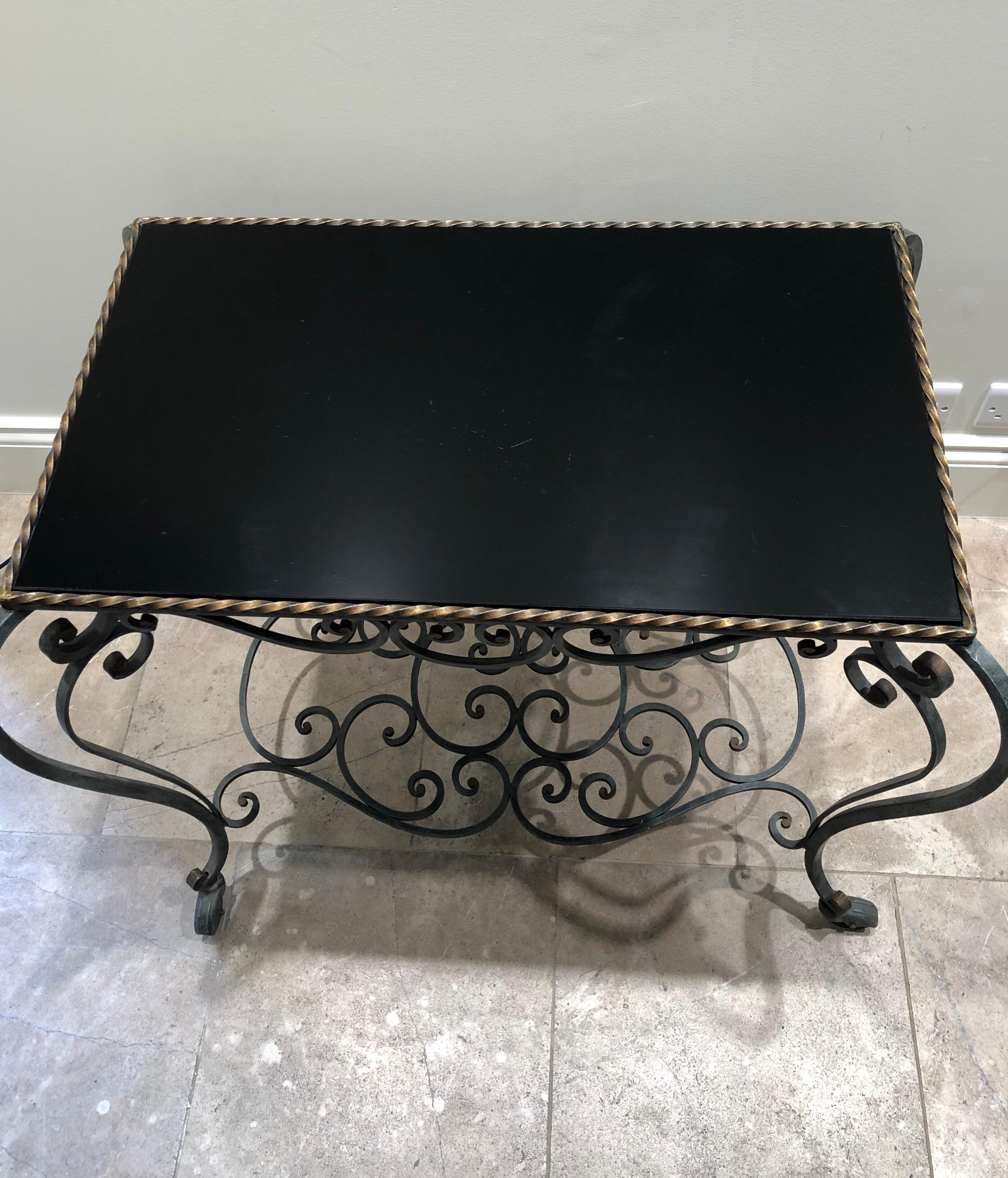Bonita mesa auxiliar francesa de hierro forjado y cristal negro con ruedas. Las medidas de la mesa real son 74 x 44 cm.