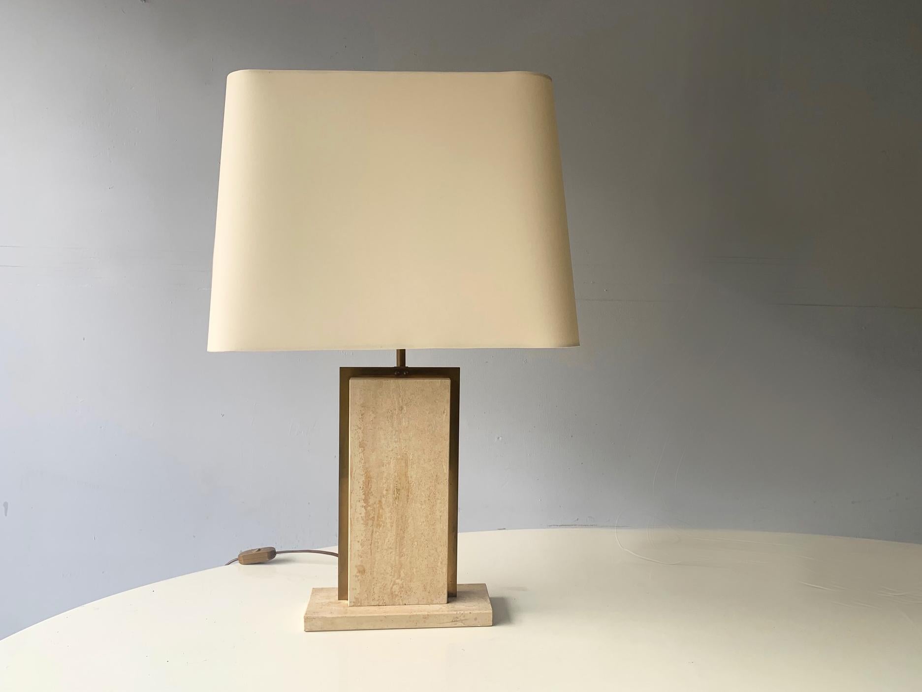 A French table lamp produced in the 1960s with solid travertine marble and inlaid gilt metal. The shade frame is original, and a new shade has been made to fit, with near identical material. There is a small mark on the shade, please see photos for