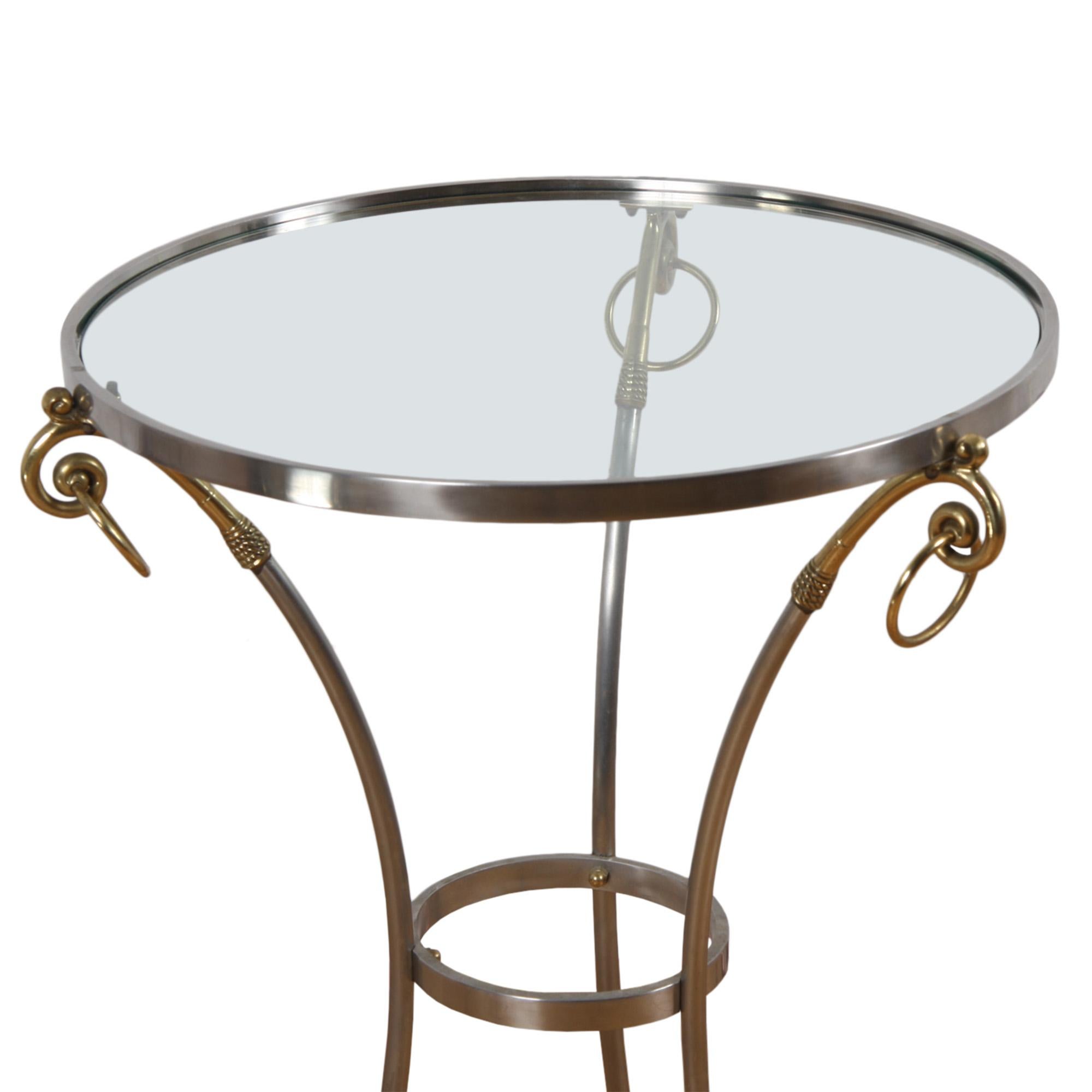 An empire style circular, glass topped side table made from brass and steel. The feet are formed from cloven hooves on the tripod stand. 

French, 1960s.

Dimensions: to confirm - the base is 46cm across, the diameter of the top is 54cm.
