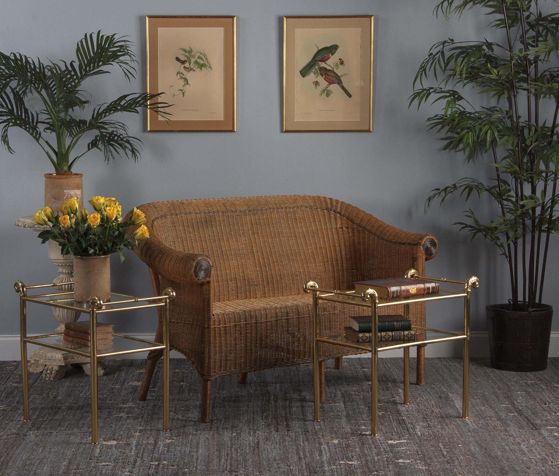 A mid-century vintage brass and glass side table from France, circa 1950s or 60s. Made of tubular brass frames, with two clear glass shelves. Each corner is topped with scrolled brass pieces that have Louis XVI design elements, including escargot