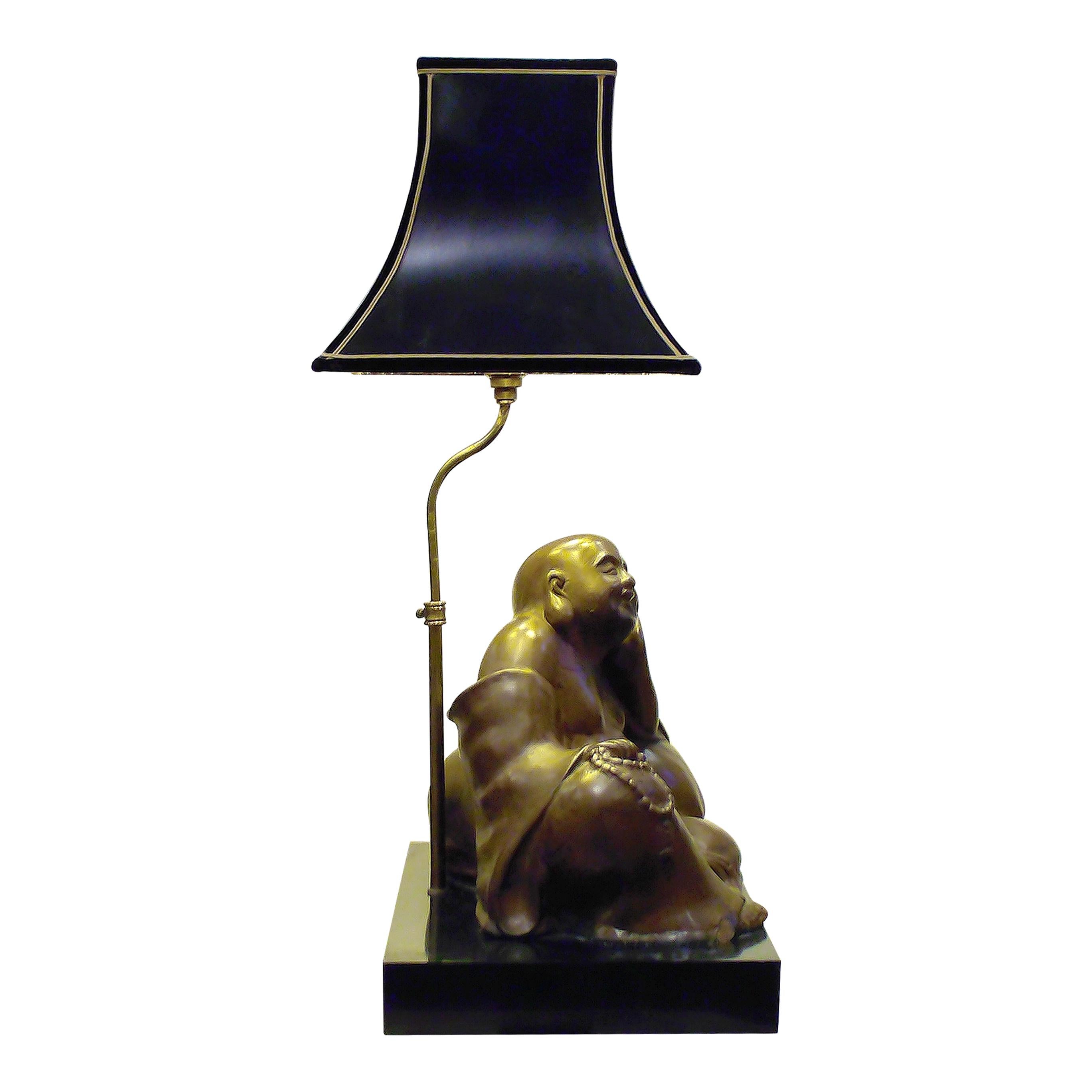 Remarquable lampe de table française du milieu du siècle, représentant une figure de Bouddha en bronze finement coulée, reposant dans une pose détendue et joyeuse sur un socle en marbre noir. L'abat-jour original de style pagode, fini en noir avec