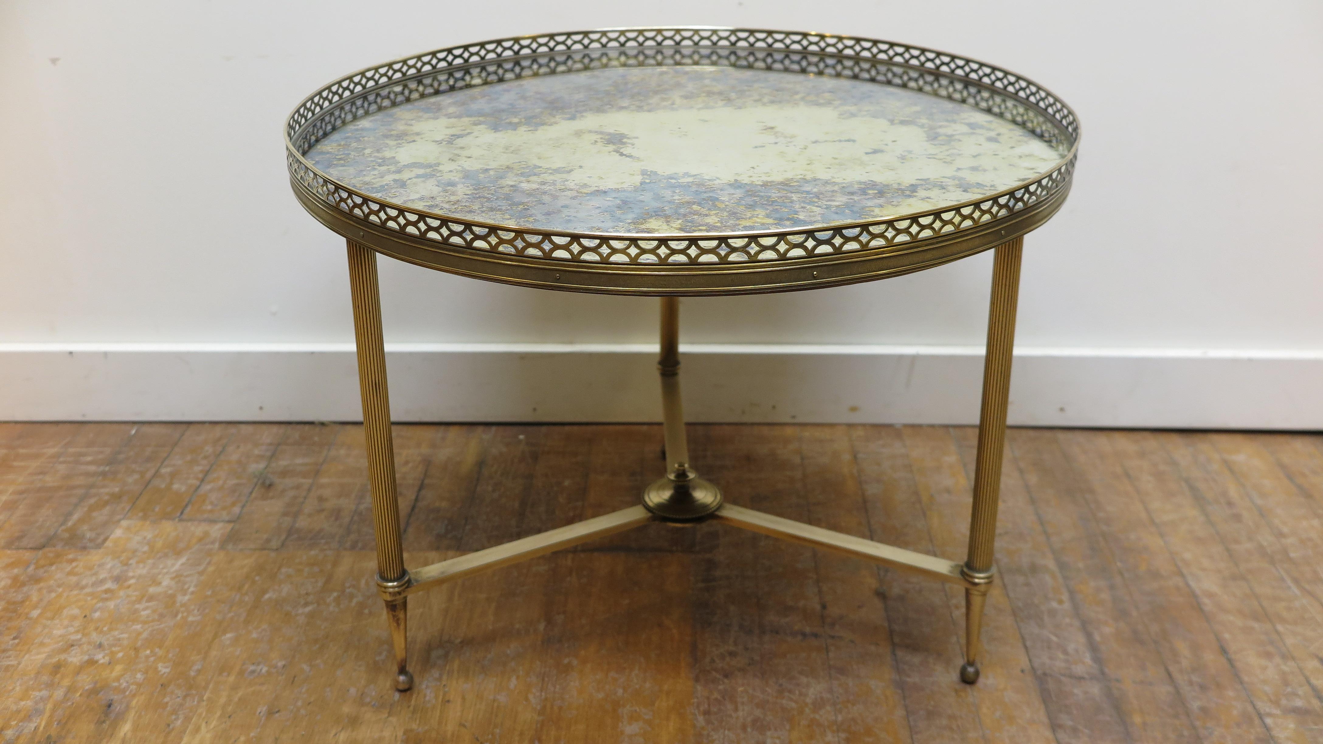 French bronze mirror top round cocktail table attributed to Maison Baguès. An elegant neoclassical style cocktail or side table having solid bronze and brass construction with a blotted mirror eglomise top all trade marks of Maison Baguès. French