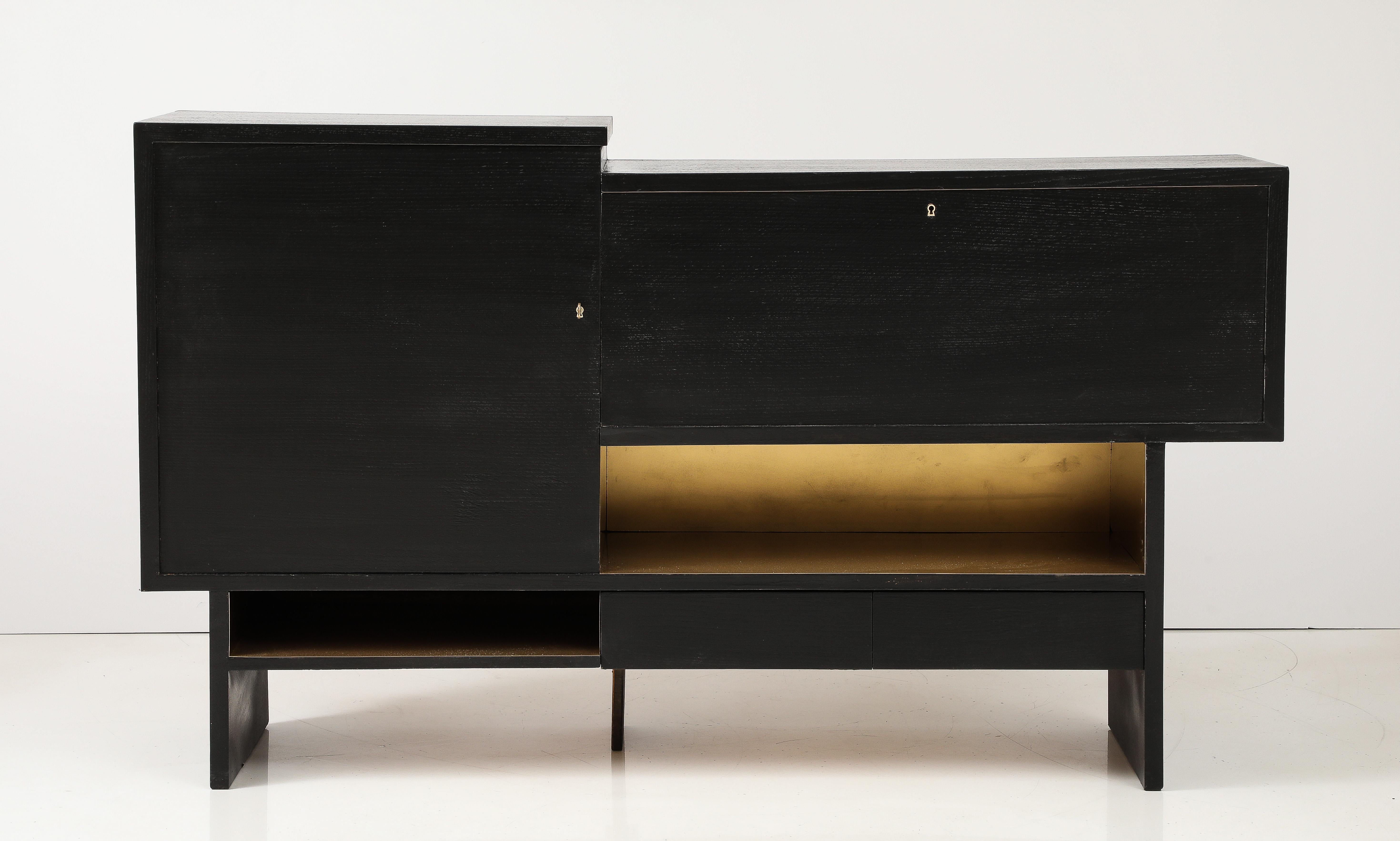 French Mid-Century Bar Cabinet with an ebonized oak exterior, having a stepped top, with the left side door opening to a shelved interior and the right side having a fall front door with shelved interior. All over two bronze clad open spaces and two