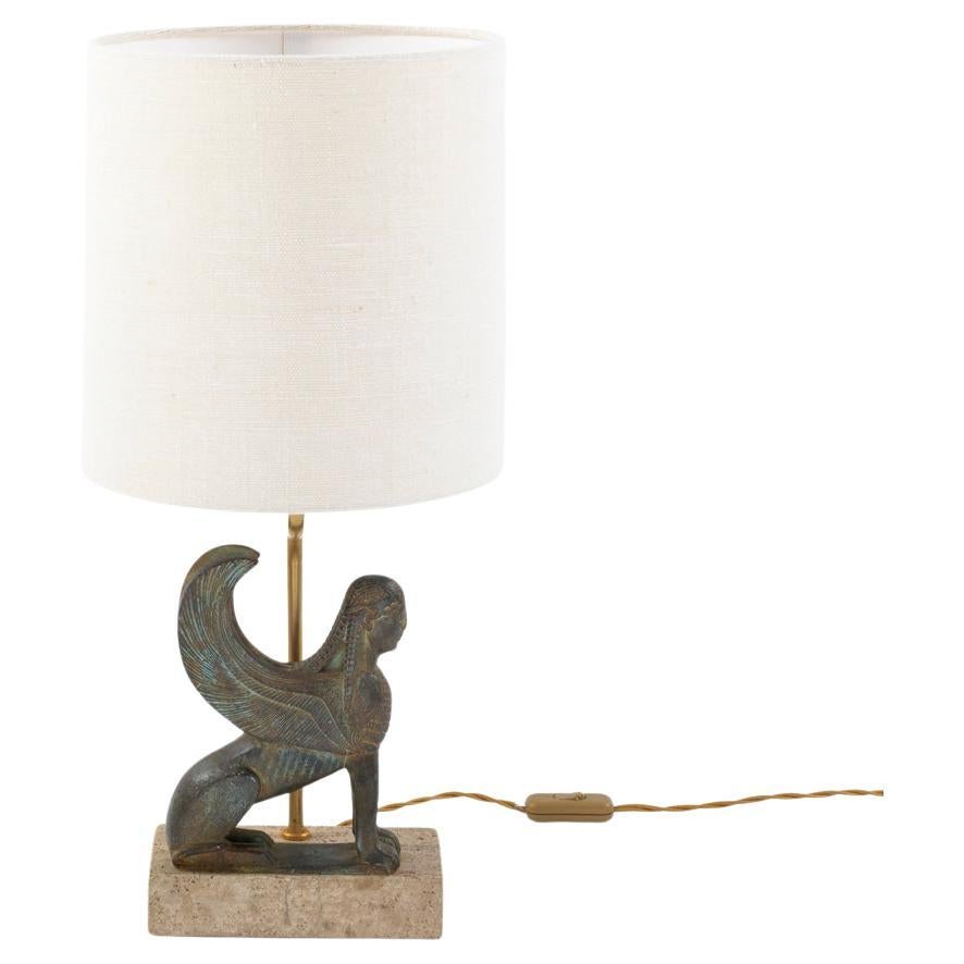 French mid-century bronze cast sphinx table lamp by Maison Le Dauphin 1970s.

The sphinx sits gracefully and upright on the rectangular, open-pored travertine base (18 x 9 x 4 cm). 
The back of the base has a small black and gold label with 
