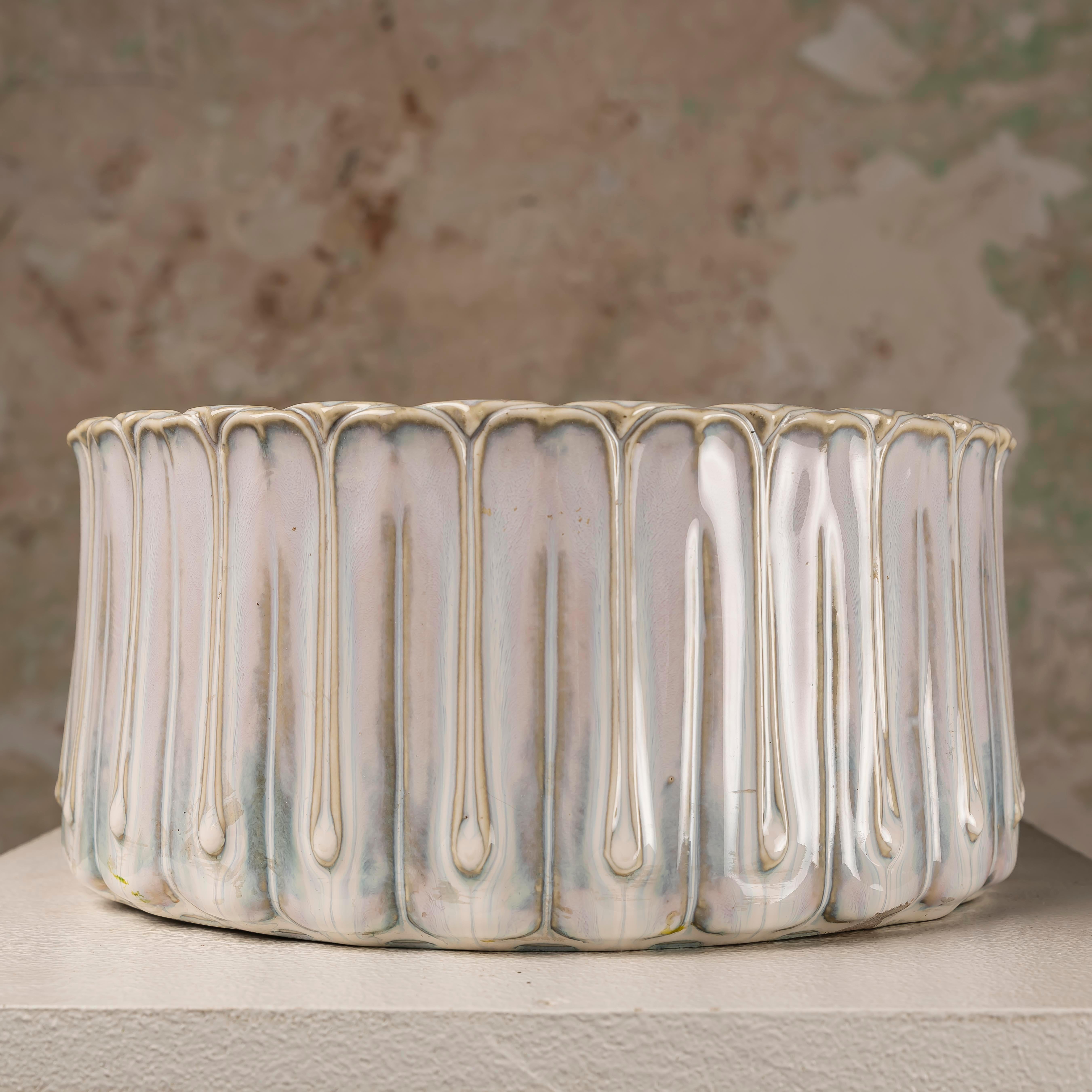 his French mid-century ceramic centerpiece was crafted in Vallauris, France, circa 1960s. The generously sized bowl, measuring 12 cm in height and 25 cm in diameter, features a refined cylindrical shape enriched with vertical molded reliefs. Its