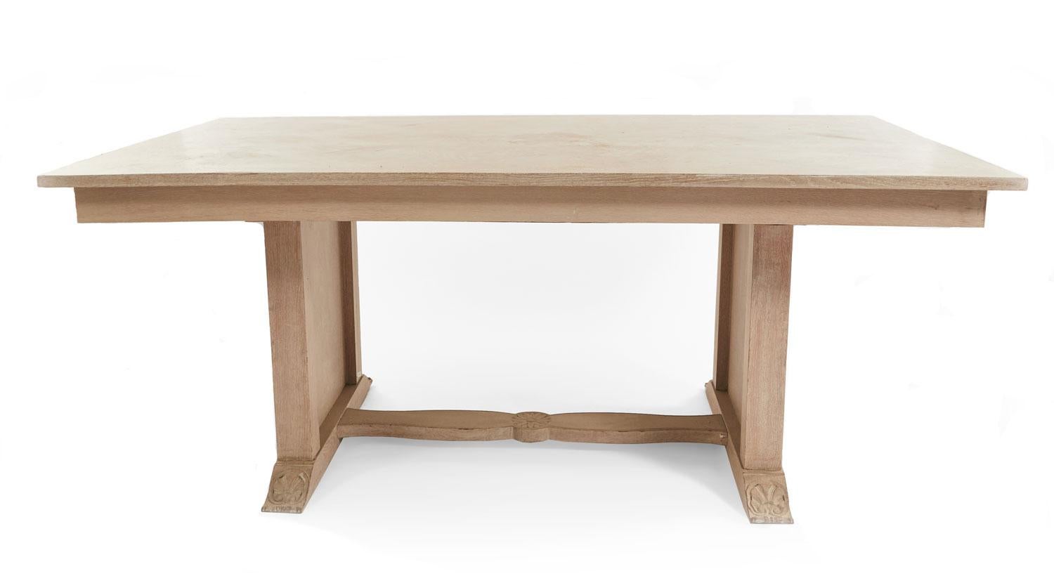 Table de salle à manger en chêne cérusé blanchi du milieu du siècle dernier, avec une base à brancard présentant des détails sculptés et un médaillon en bronze doré sur des pieds en panneaux latéraux.

Table légèrement déformée