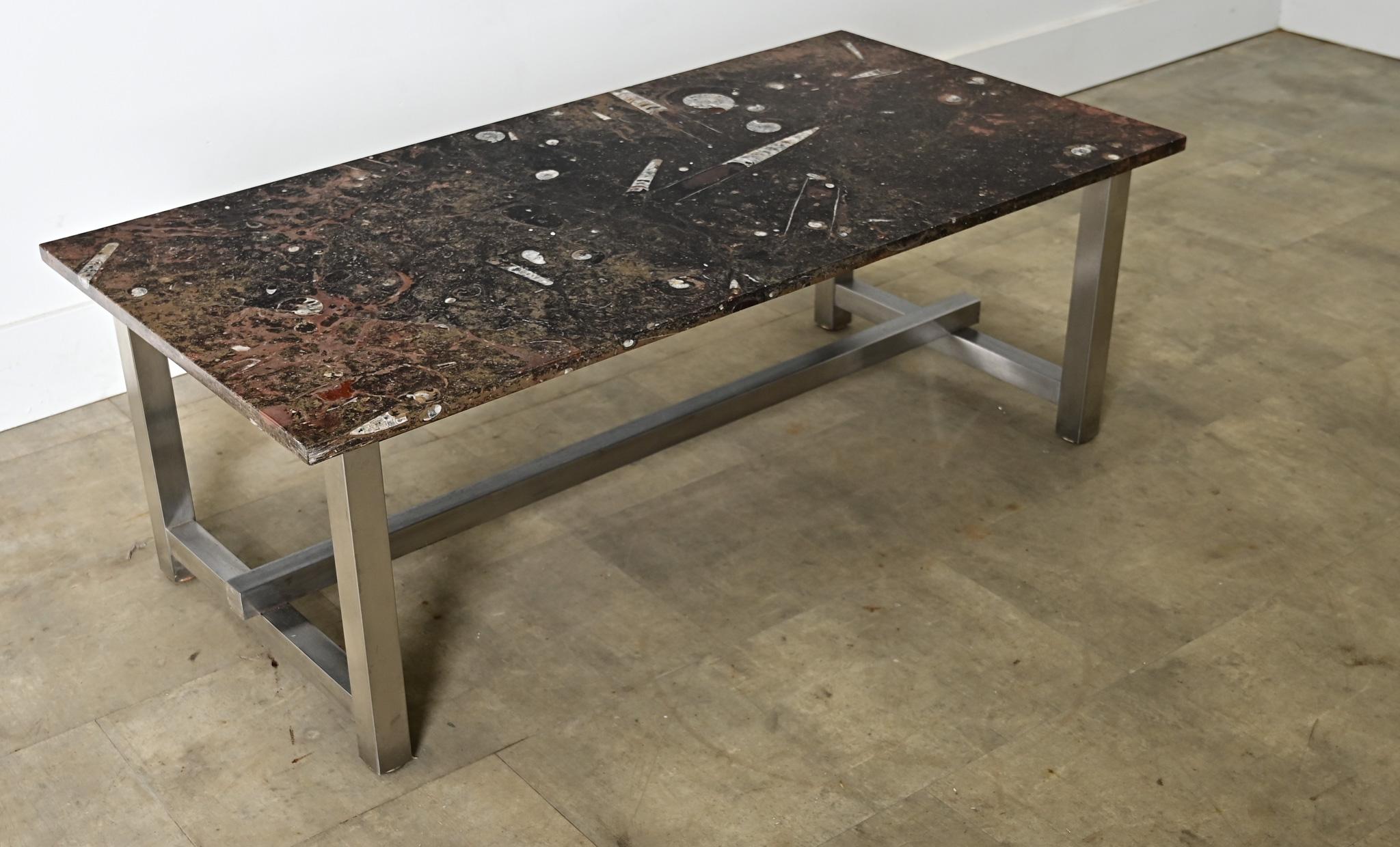 French vintage mid-to-late 20th century coffee/cocktail table featuring an impressive slab of marble with inclusions of fossilized marine life. The brown-black stone reveals painterly infusions of sienna-toned veining clouding the dark marble,