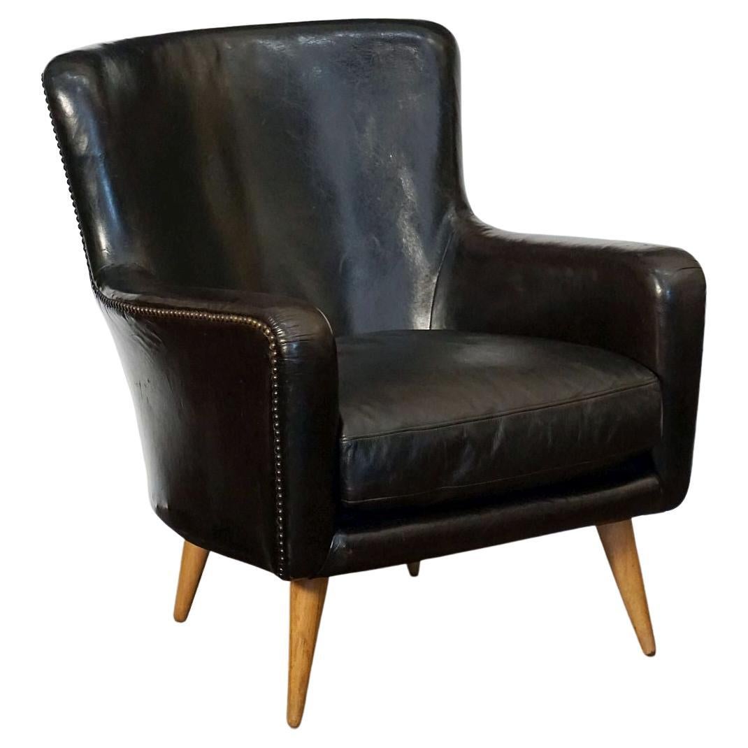 A handsome pair of mid-20th century French club or lounge chairs, each chair featuring a stylish Modern back and sides with comfortable drop cushion seat - in original black leather with beaded brass stud accents, on turned tapering legs.

Two