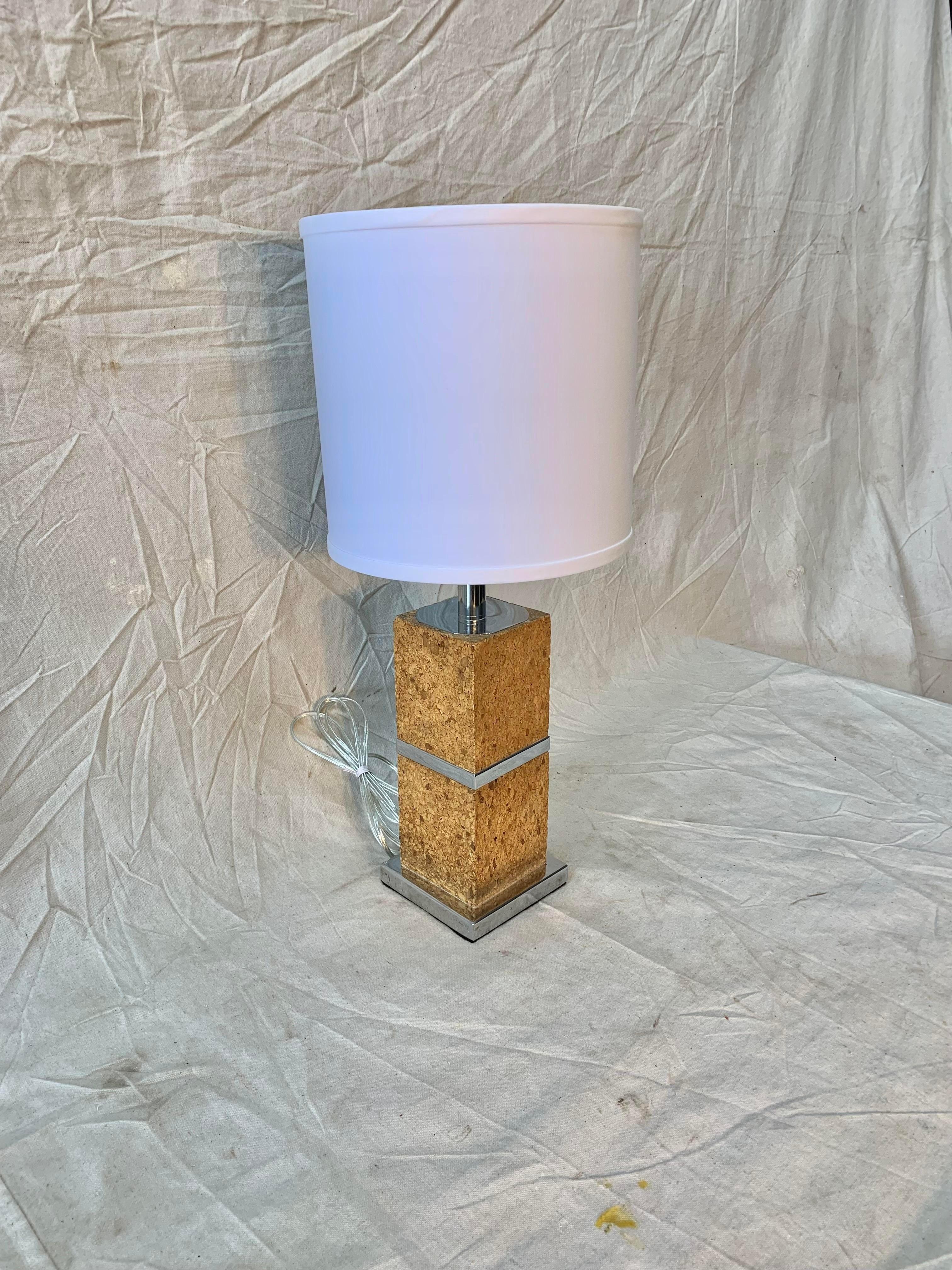 Cette lampe de table en liège et chrome a été fabriquée dans les années 1970. La lampe se compose d'une base carrée chromée surmontée d'une colonne carrée en liège avec une bande chromée au milieu. Dans les années 1970, le liège était l'un des