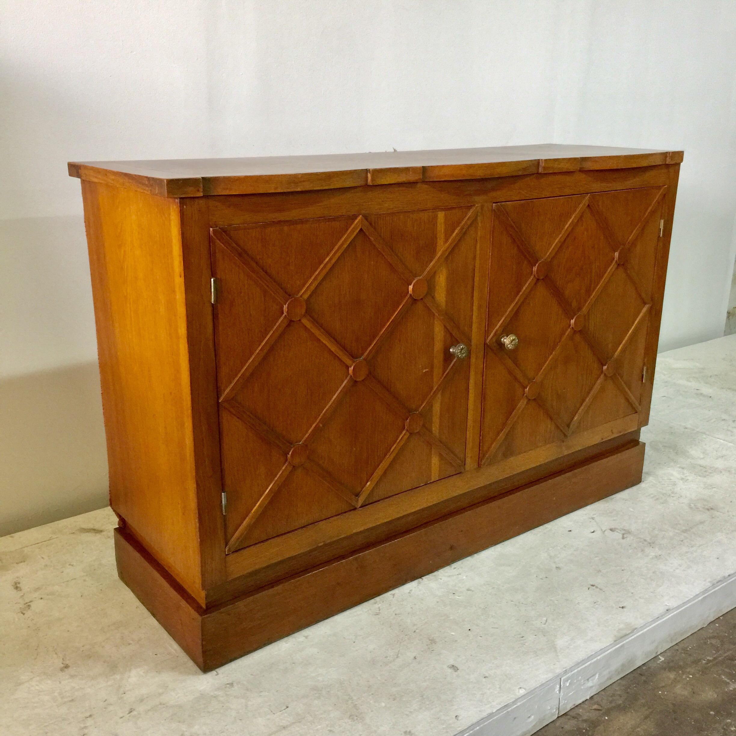 This piece was customized for a specific commercial space in 1940s in the style of Jean Royère. 2 doors open to open shelving. The sides of this cabinet are being left “as found” which was likely inserted in to a niche space. This is all oak. Note: