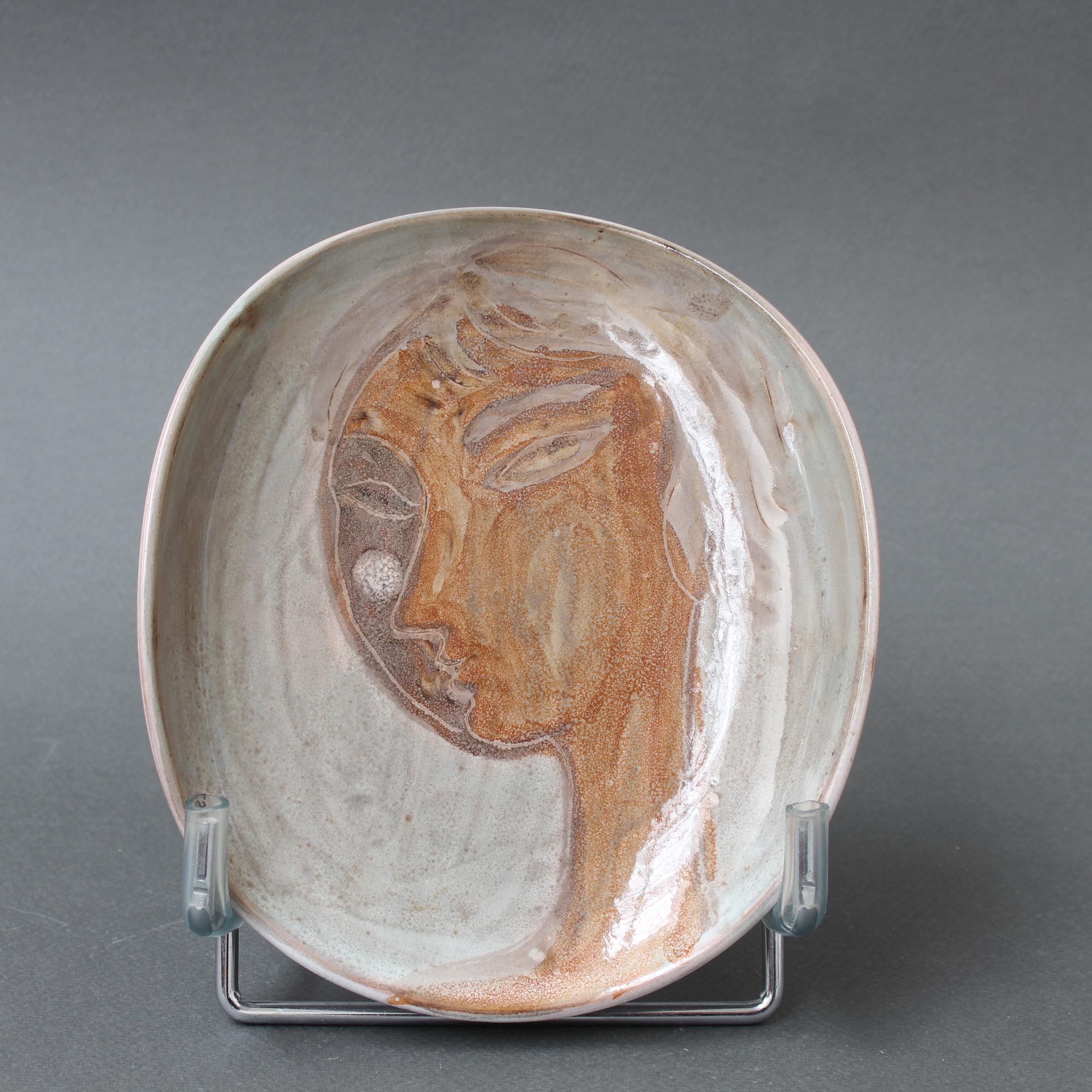 Plato de cerámica curvada francesa de mediados de siglo, pintado a mano con el rostro de una mujer con el pelo corto, por Atelier du Grand Chêne (hacia la década de 1950). La pieza es absolutamente encantadora y tiene un tufillo a Picasso; de hecho,