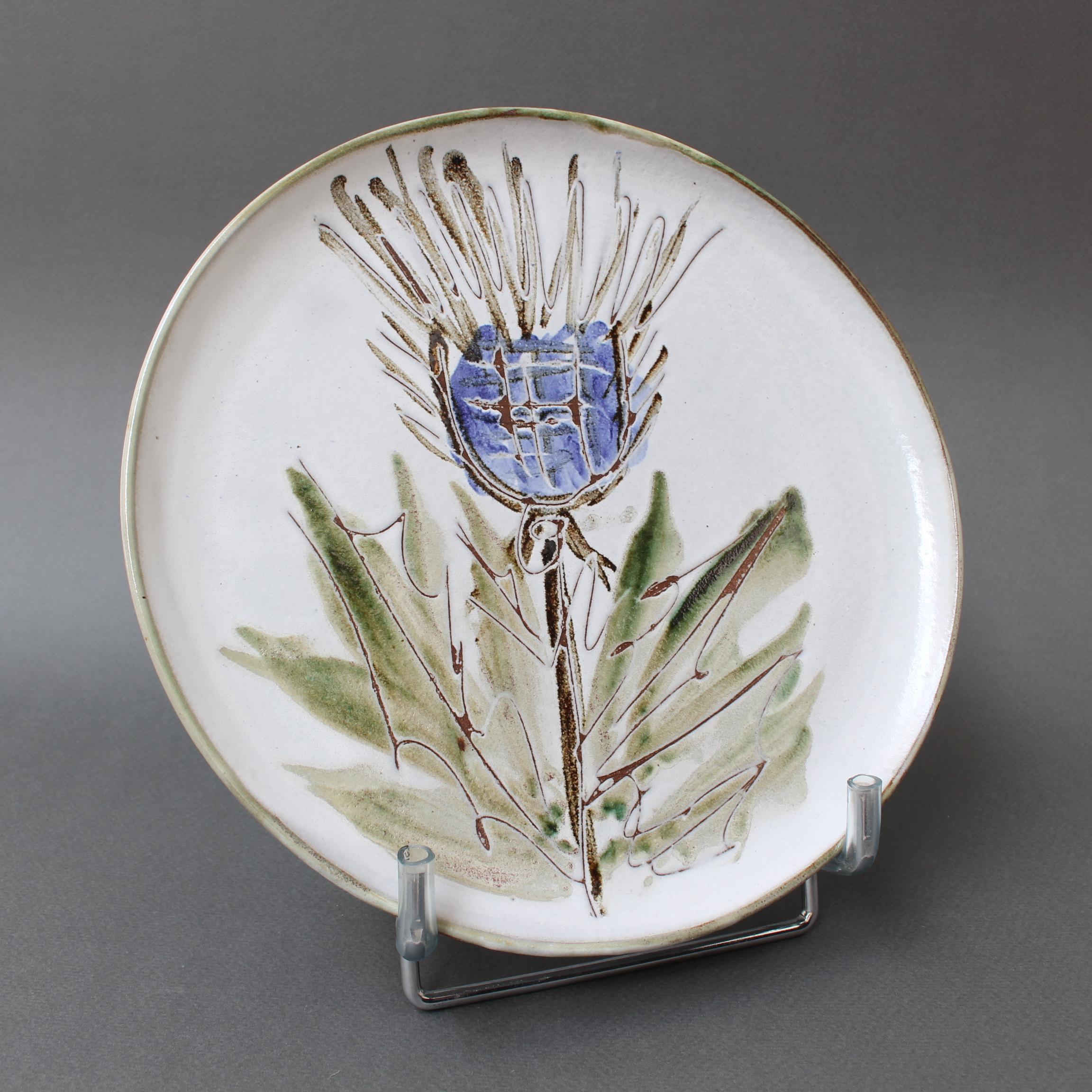 Mid-century decorative plate (circa 1960s) by Albert Thiry. A chalk-white glaze provides the background for a colourful thistle motif in the centre recess of this small dish. The incised plant has depth and adds a tactile element to the piece. The