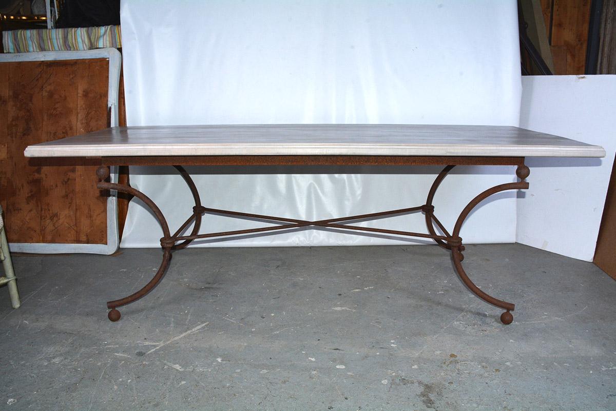 A French vintage country wood top farm table with iron base. The base of the table is comprised of four curved legs connected by centre X form reminiscent of neoclassical form. The tabletop is has a hand rubbed wax finish. We love the perfect