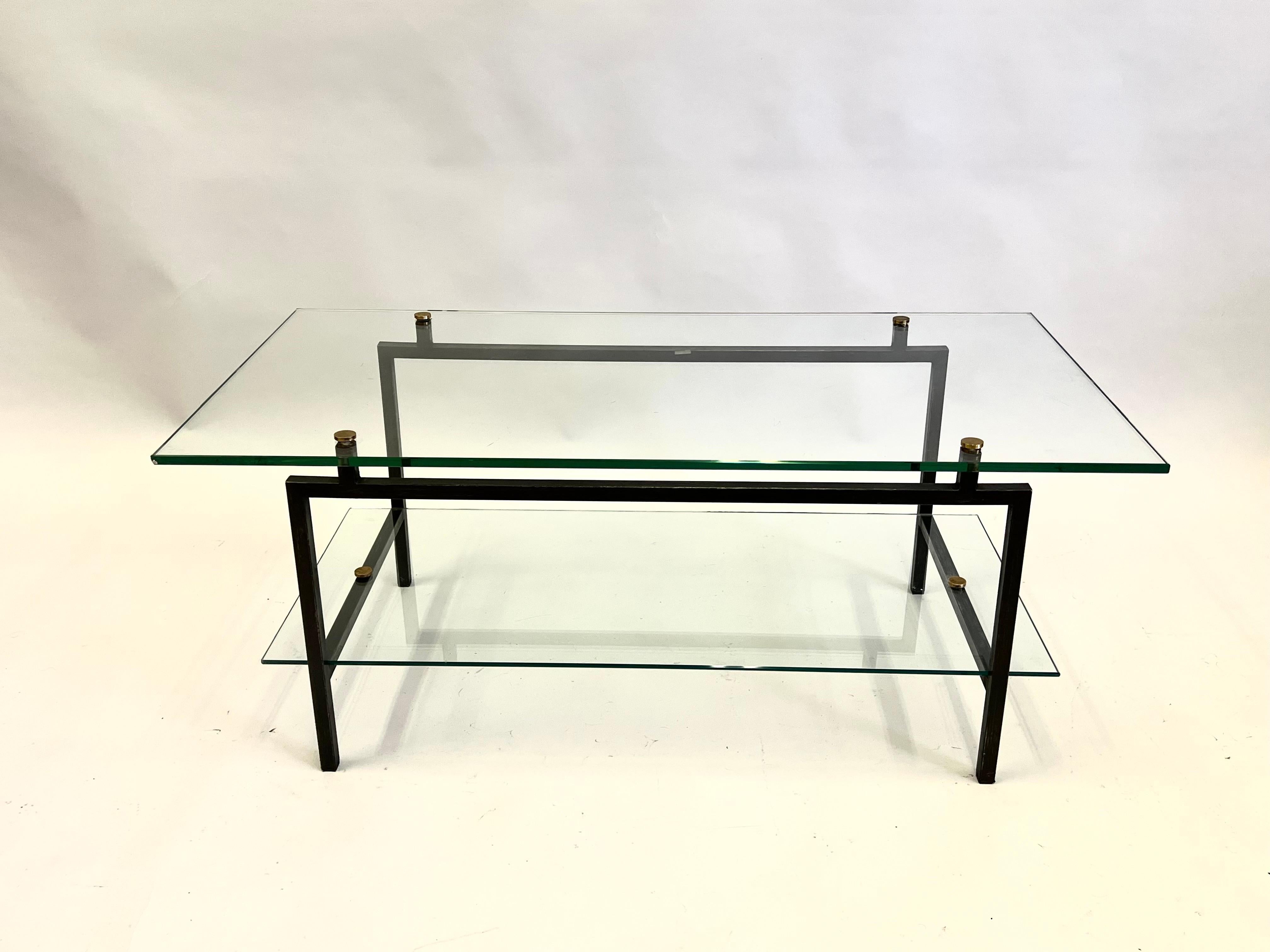 An elegant and pure Modernist Statement, a rare French Mid-Century Modern double tier coffee table in black enameled steel and glass with brass details by Pierre Guariche, circa 1950-1960. 

This original double tiered cocktail table features