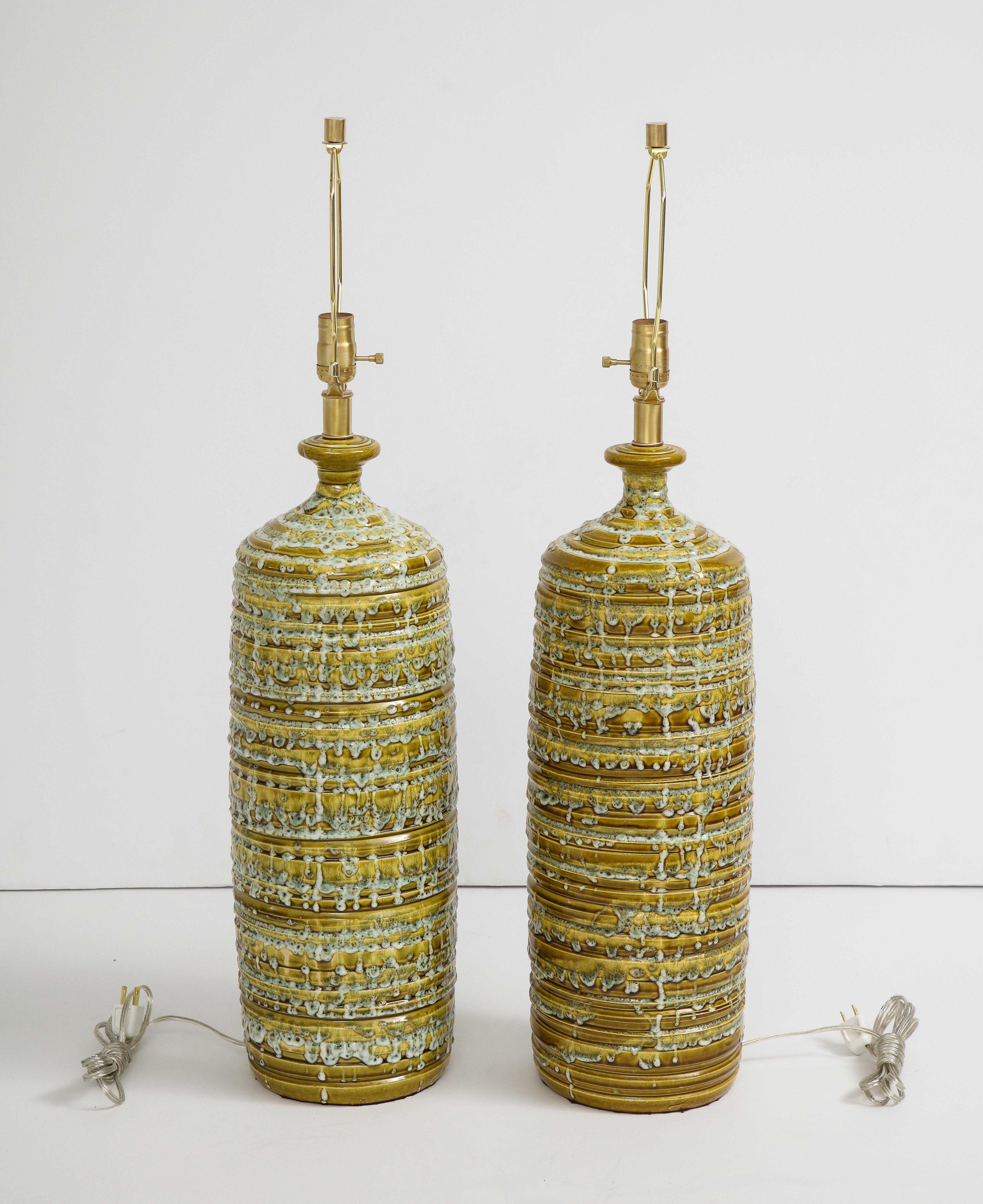 Exquisite pair of bottle form ceramic lamps in moss and loden green and off white glazes. Rewired for use in the USA, 100W bulbs. Satin brass hardware.