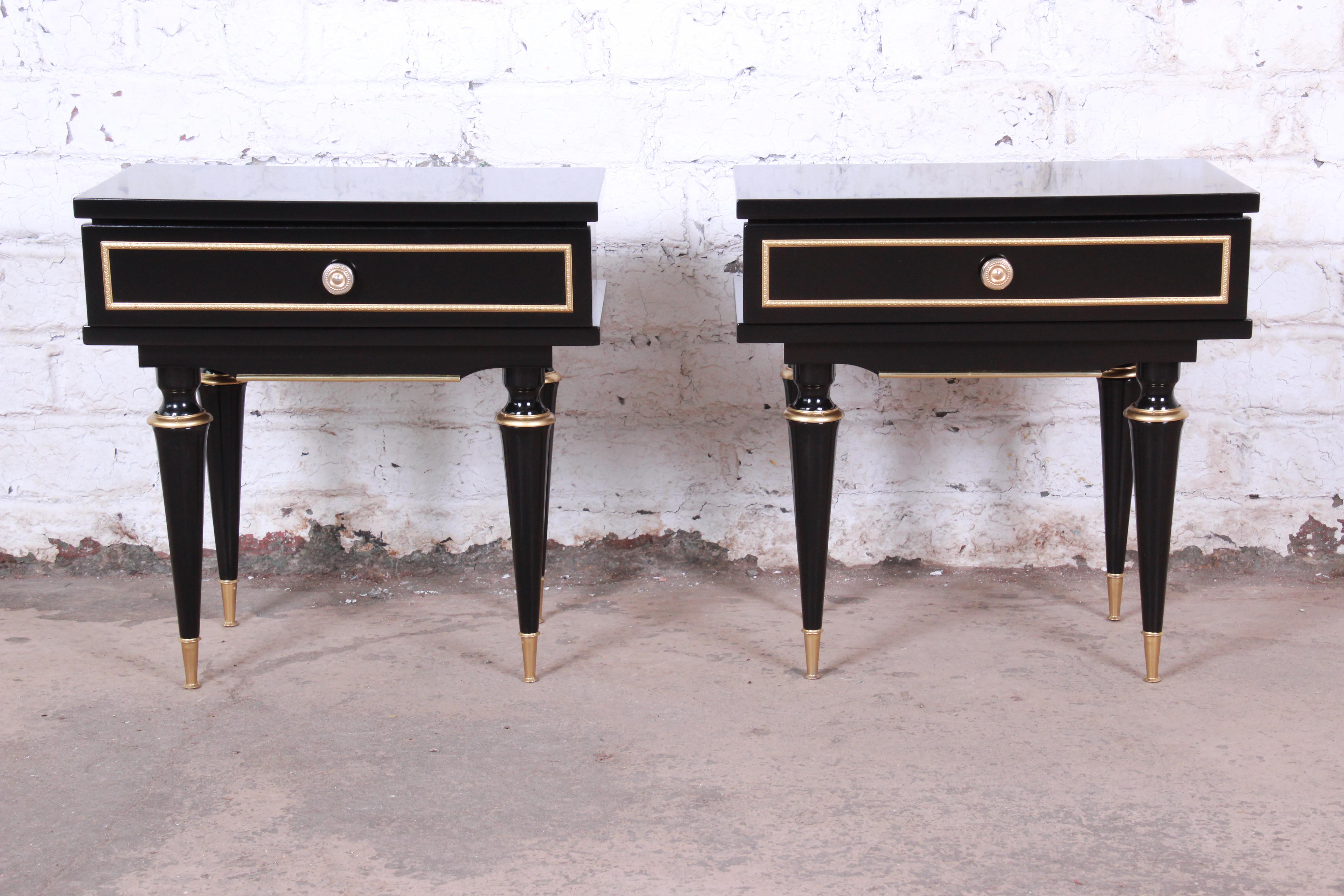 An outstanding pair of French Mid-Century Modern nightstands or end tables. The nightstands feature a high gloss ebonized finish with gorgeous brass-tipped feet, trim, and accents. They each have a single dovetailed drawer. The nightstands are