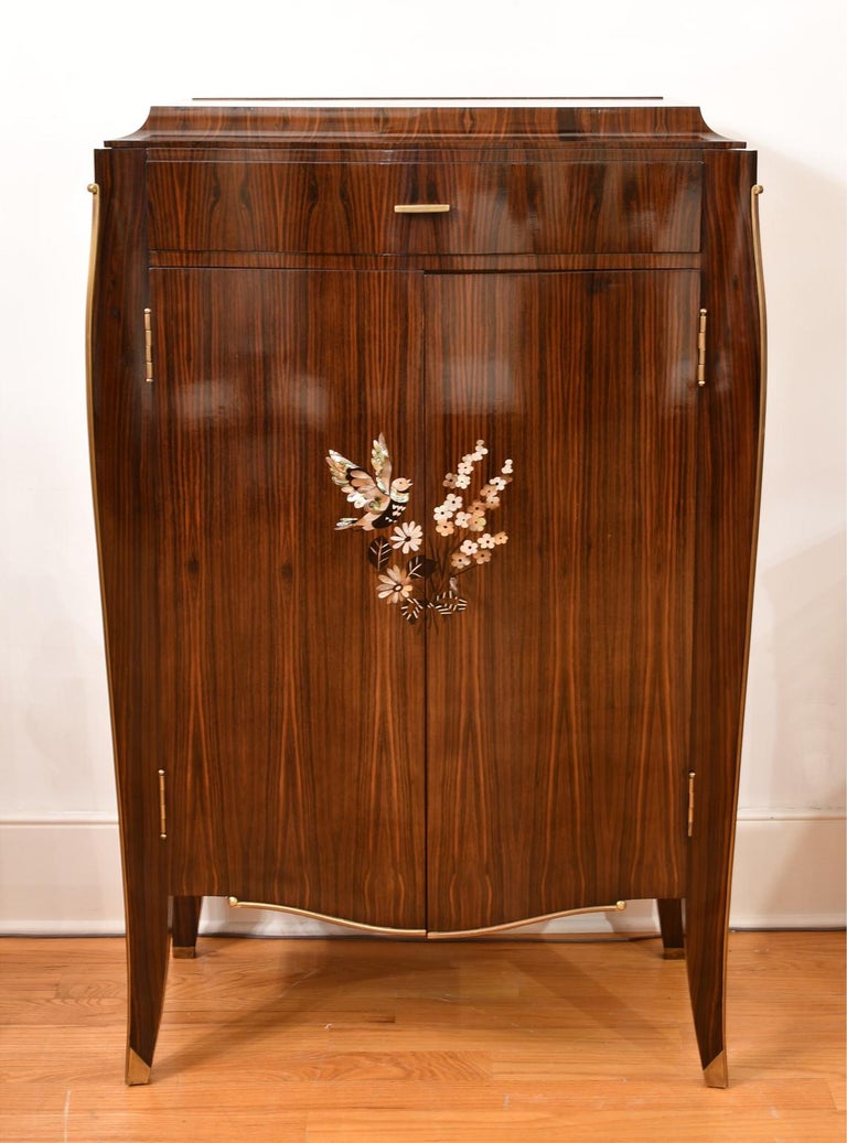 An exquisite mid century bar by famed French Art Deco furniture designer, Jules Leleu (1883-1961), in fine Maccasar ebony with marquetry inlays in ebony, abalone & mother of pearl depicting a bouquet of flowers & a dove with outstretched wings.