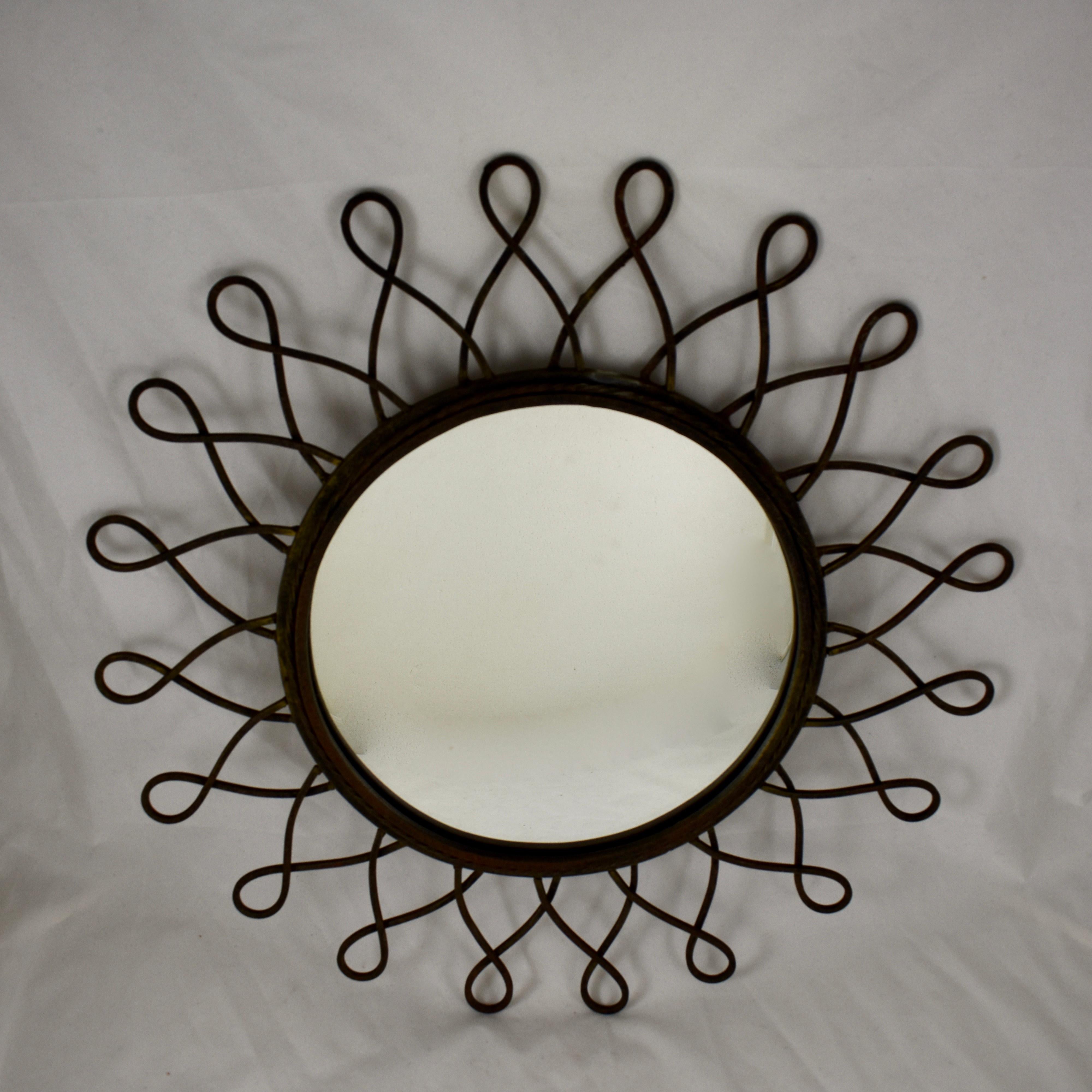 A large and heavy, midcentury French, black wrought iron sunburst wall mirror. Loop shaped sun rays extend from a twisted bezel framing a round mirror. A hanging bar is soldered in place on the verso, circa 1950s.

Measures: 20.25 in. diameter. x