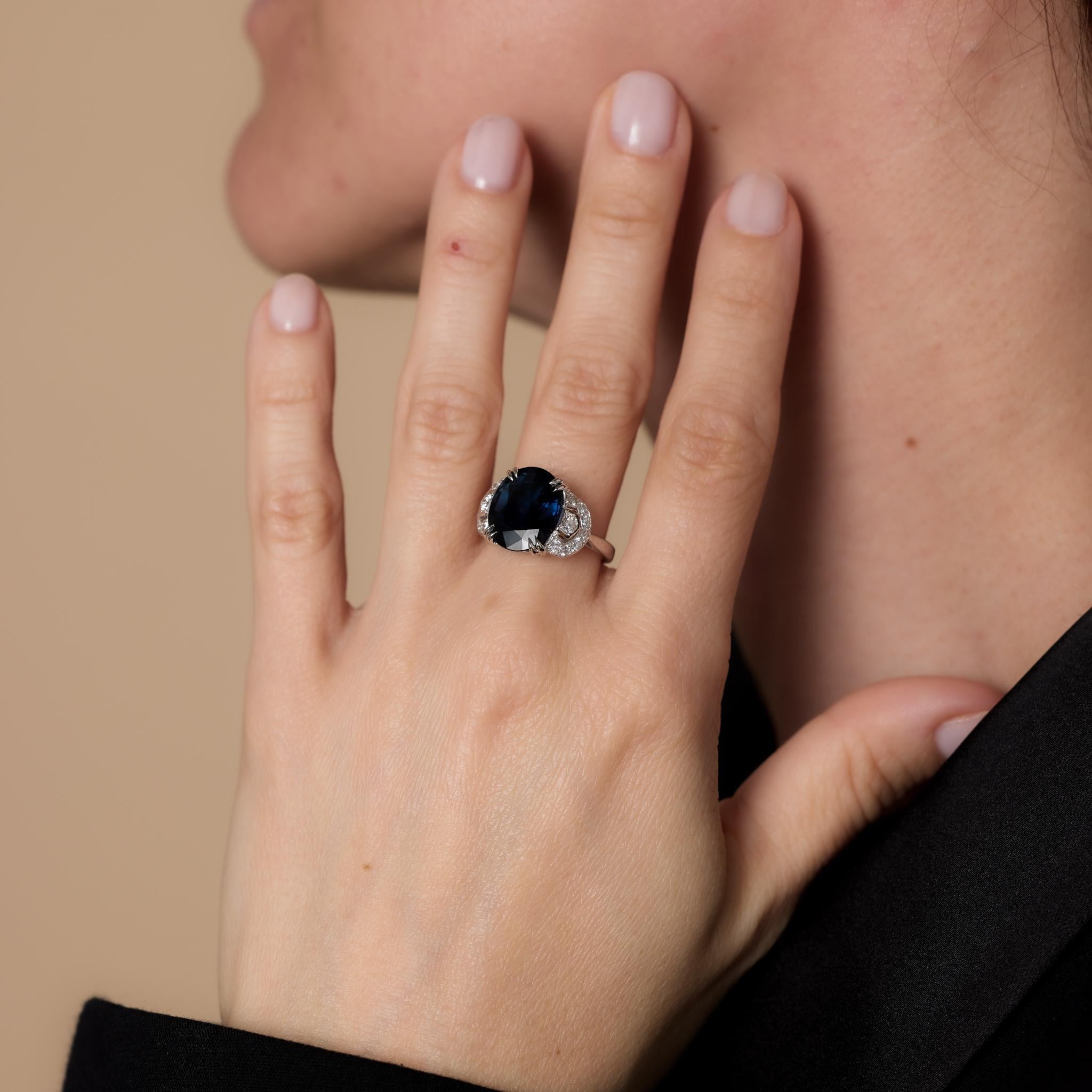 Questo anello da cocktail in platino francese del Mid-Century mette in mostra uno zaffiro thailandese riscaldato dal taglio ovale certificato GIA da 5,31 carati, arricchito da 16 diamanti tondi taglio brillante per un totale di 0,30 carati, colore