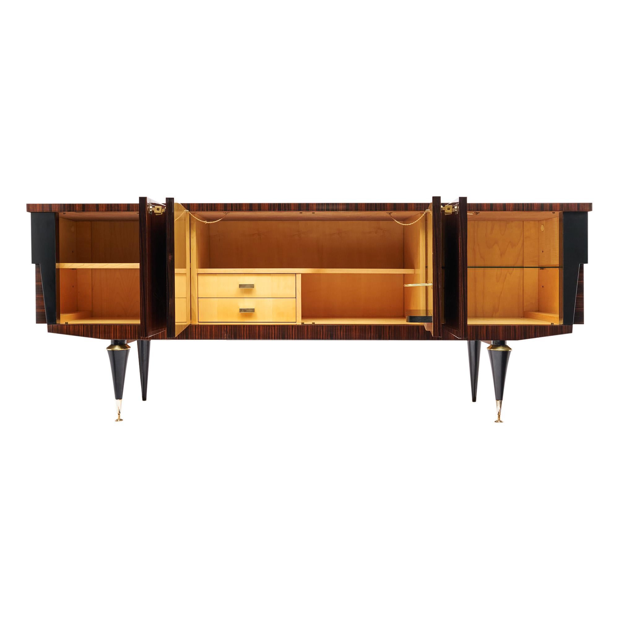 Buffet from mid-century France featuring a Macassar of ebony veneer combined with stylized lemonwood inlays. The four doors open to interior shelving with working locks and keys. The interior features wood shelving, glass shelving, a bottle and the