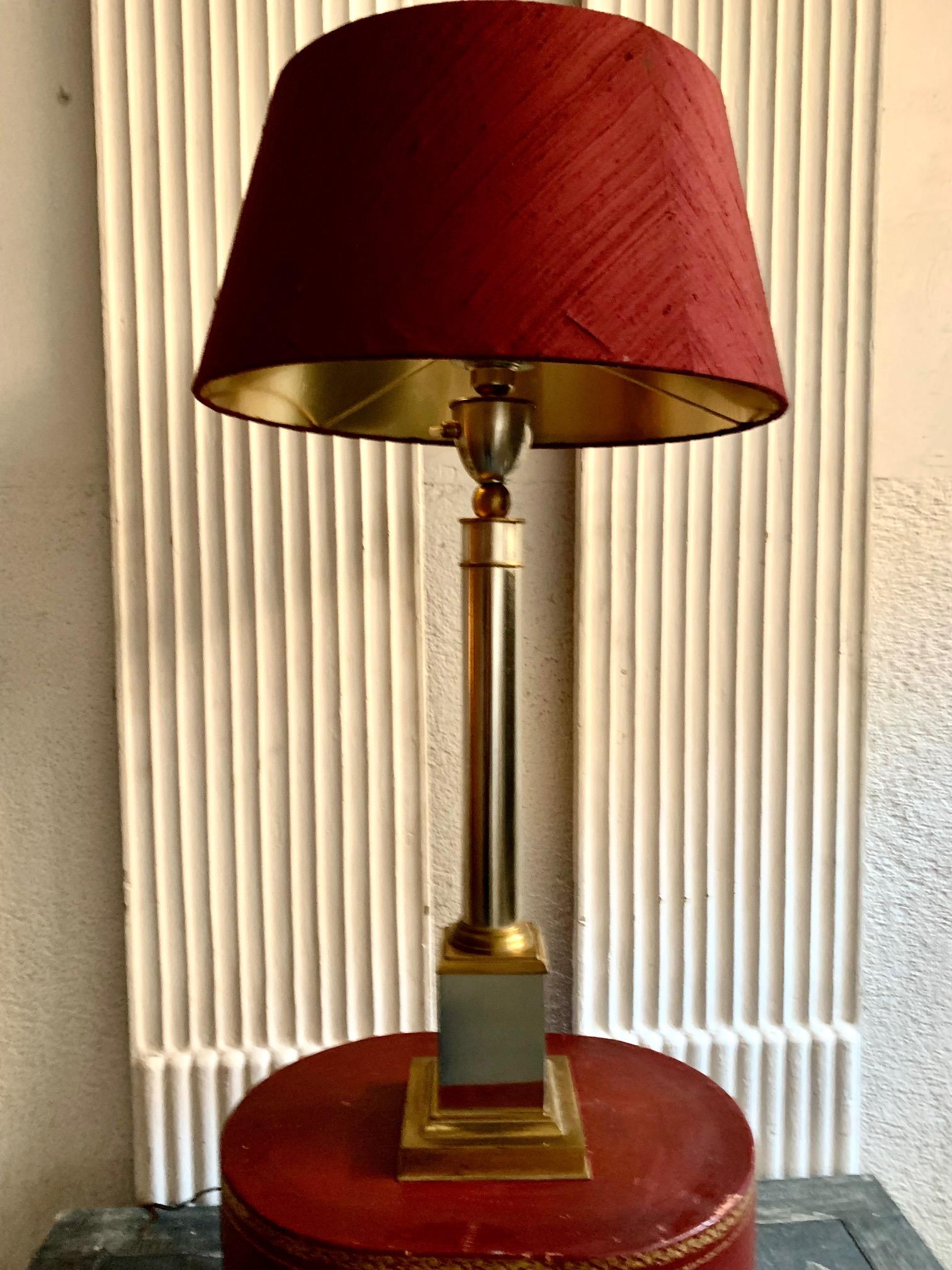 An elegant table lamp attributed to Maison Jansen, in brass and chrome silver metal, in the shape of a column.
The lampshade is made of garnet silk with a gold interior. the measurements of the lamp is without the lampshade, the measurement of the