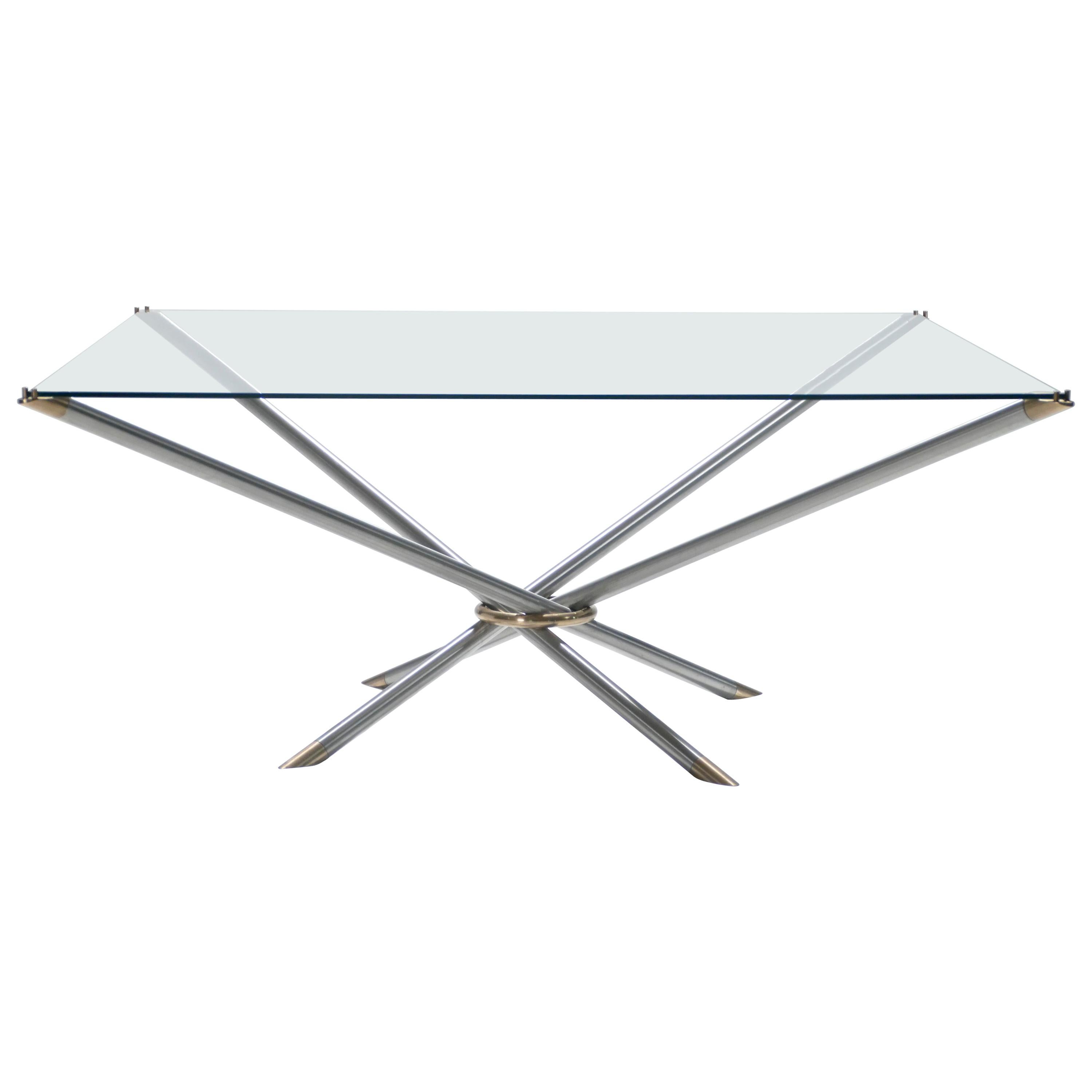 This metal, brass, and glass coffee table has the sleek, yet decadent, look that’s reminiscent of French designer Georges Geffroy. The smooth light metal legs are crossed and kept together with a brass loop, creating an inventive, geometric design