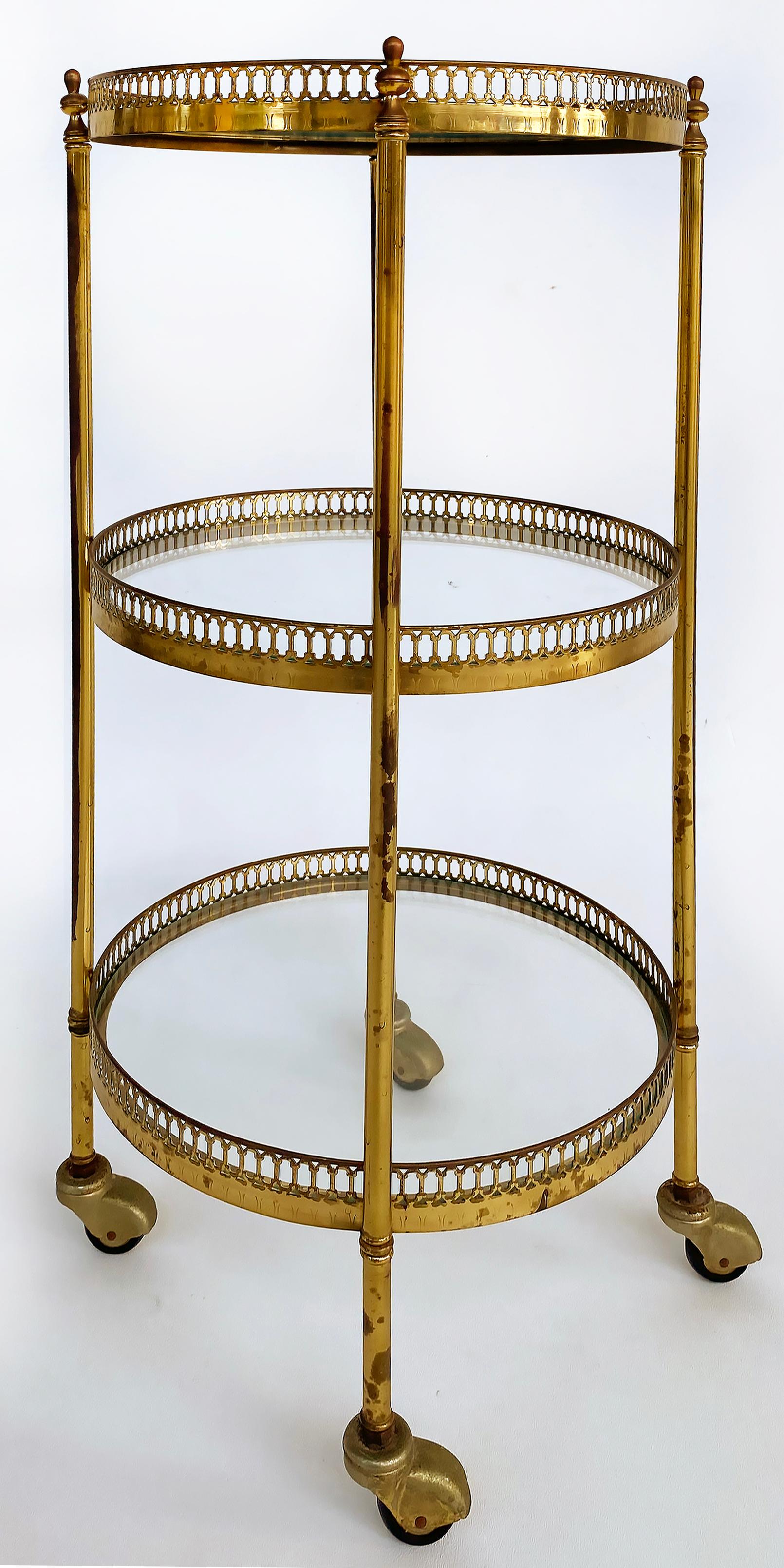 French Mid-century Modern 3-Tiered Brass and Glass Table on Casters

Offered for sale is a French mid-century modern three-tiered brass plated and glass round table on casters. The shelves have gallery rails for security. There are some areas of