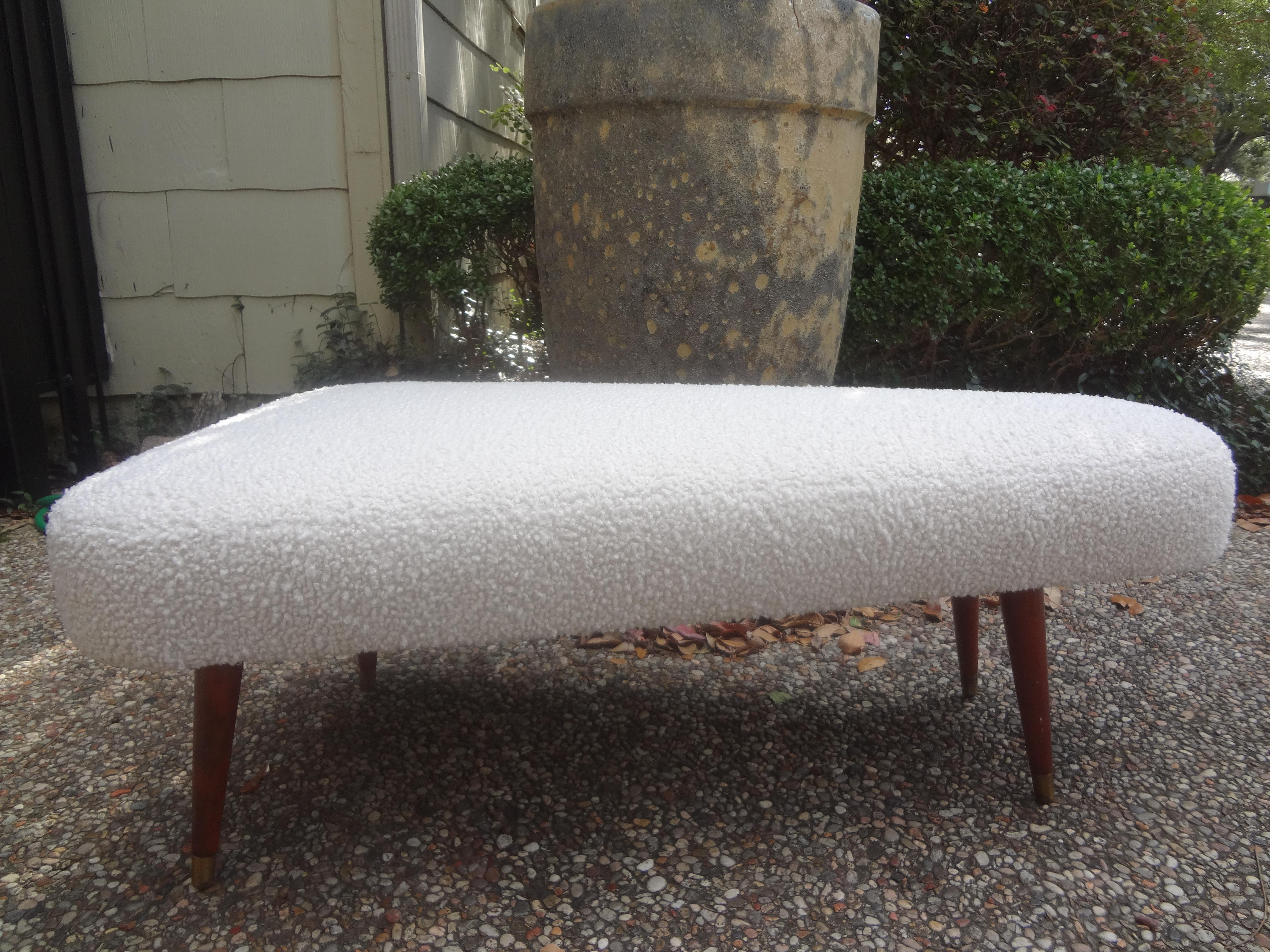 French Mid-Century Modern André Arbus style triangular bench. This unusual bench, ottoman or poof has graceful tapered legs with brass sabots and is newly upholstered in white boucle.