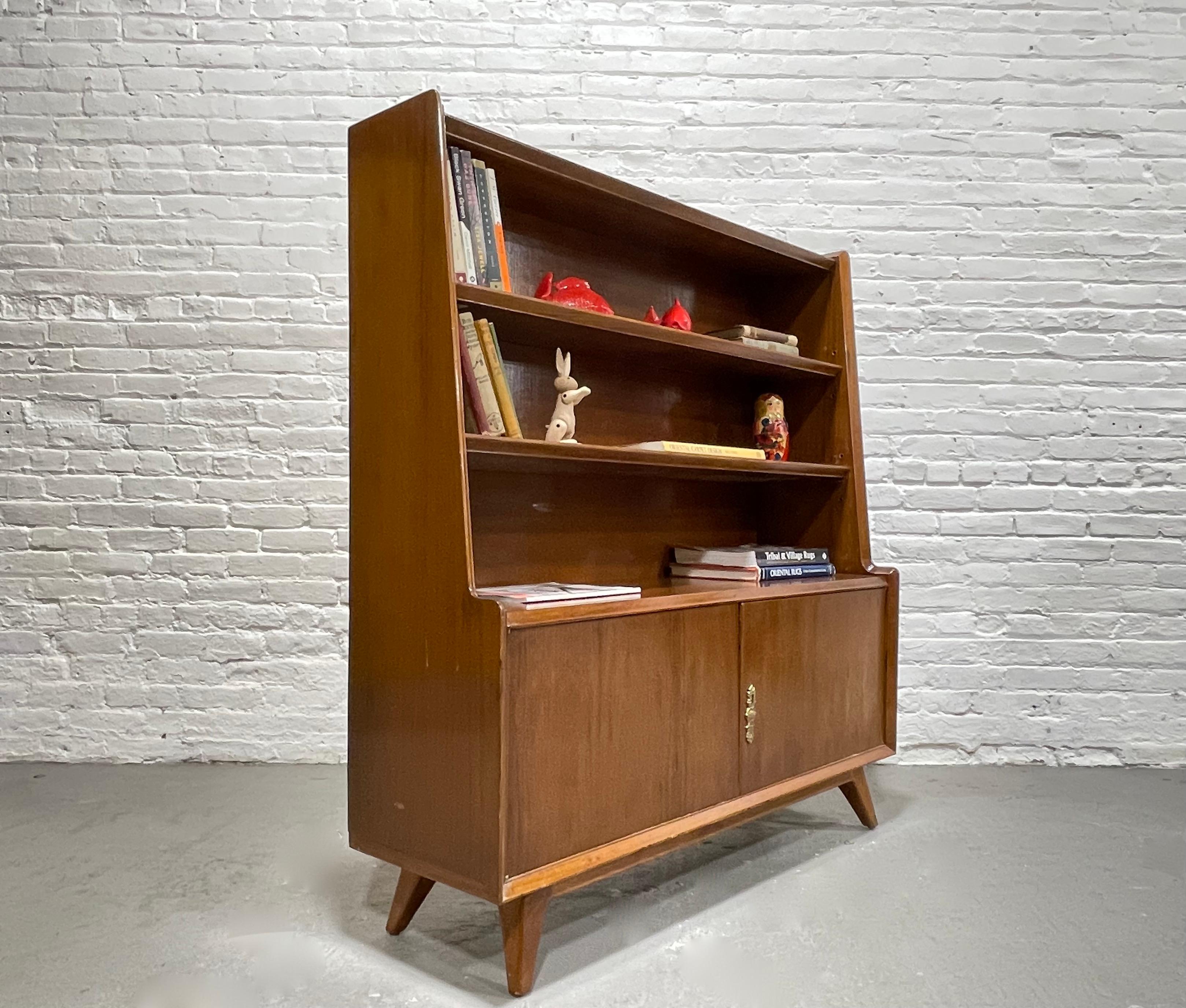 French Mid Century Modern Bookcase, c. 1950's. This incredible piece features plenty of shelving space for your books or collection and a wide open lower cabinet, perfect for storing vinyl, board games, toys or virtually anything else. Each shelf is