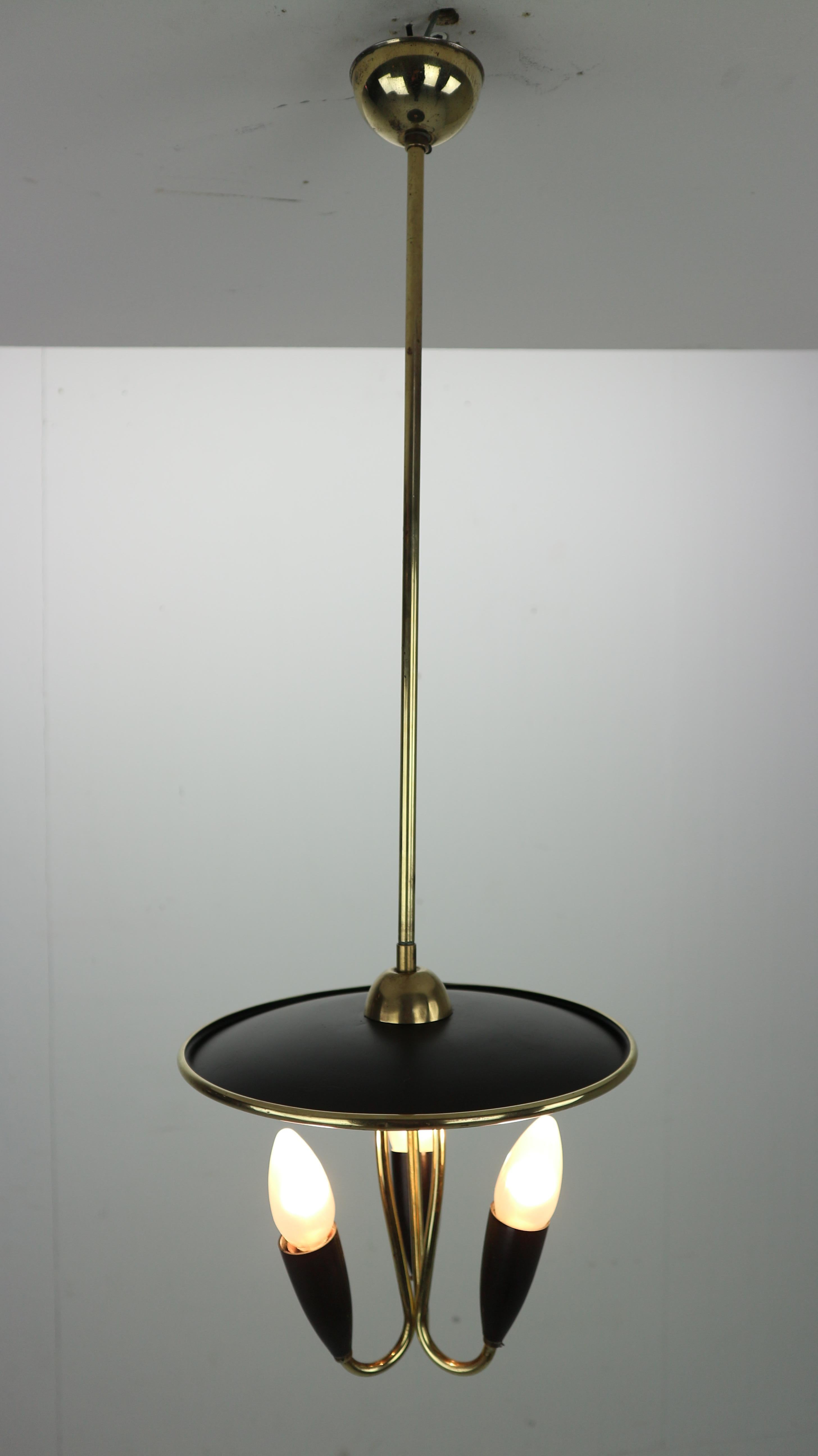 Mid-Century Modern period chandelier lamp made in 1950s France.
An elegant and typical fifties design lamp is made from black metal and brass curved details around it.
Three lamp bowl uplight lamp gives a warm light and creates a cozy atmosphere