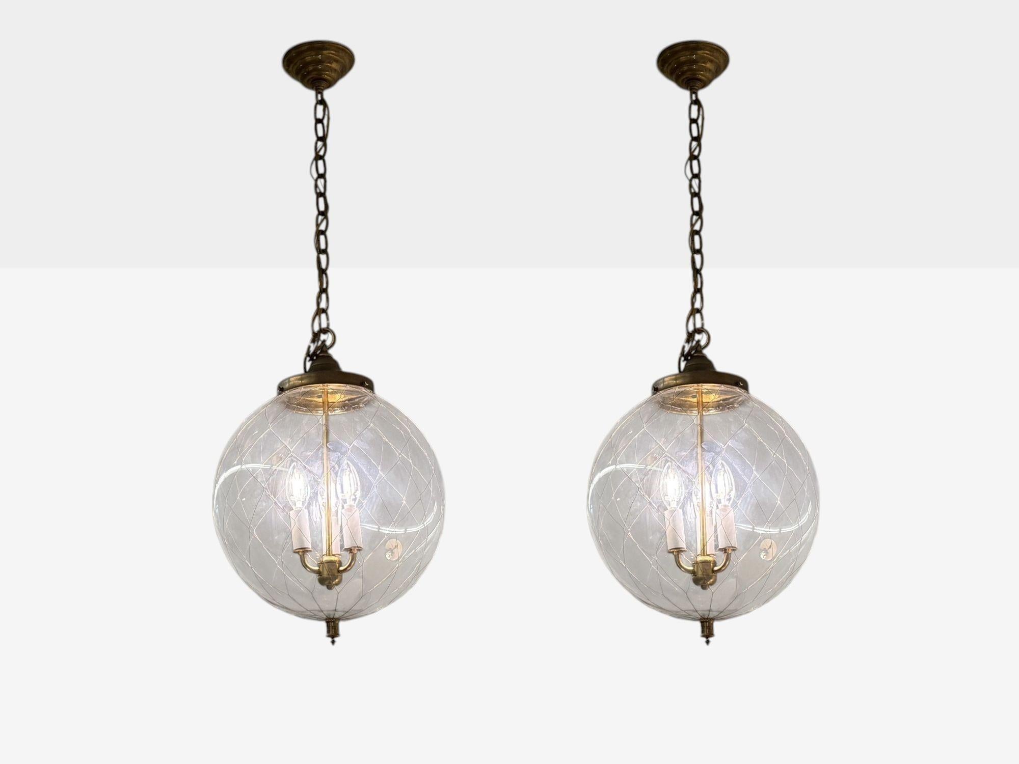 French Mid Century Modern, Brass, Blown Glass, Globe Pendant Lights,1950s

Elegant pair of finely decorated hand-blown glass globe chandeliers, each featuring a large circular dome encased in thin bronze reeding. The central fixture includes three