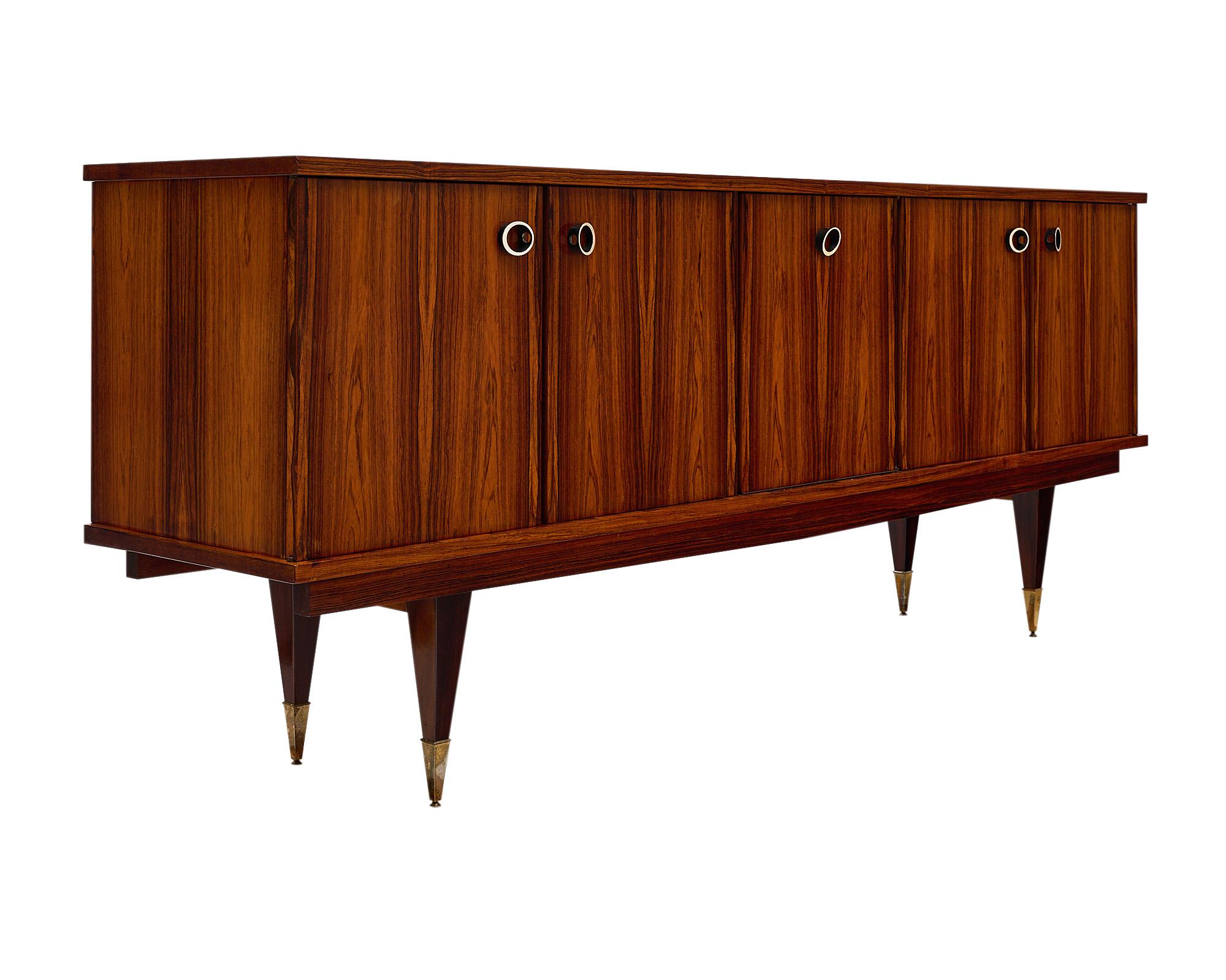 Mid-Century Modern French buffet/credenza made of solid Brazilian rosewood. This French sideboard features four cabinet doors and one drop front door opening to interior shelving and two wooden drawers for ample storage. The piece has been