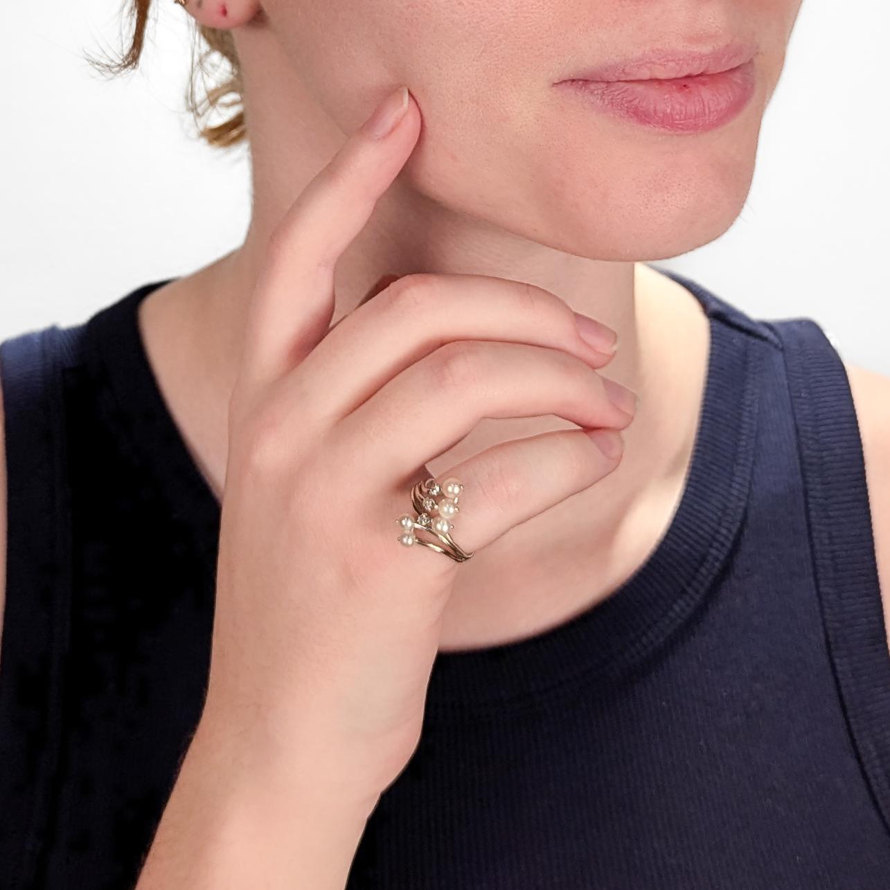 A fine French cocktail ring. 

In 18k gold.

With a modified bypass setting comprised of a split wire shank with ends terminating in bead-set cultured white pearls and prong-set single cut white diamonds. 

Marked with a slightly rubbed French eagle