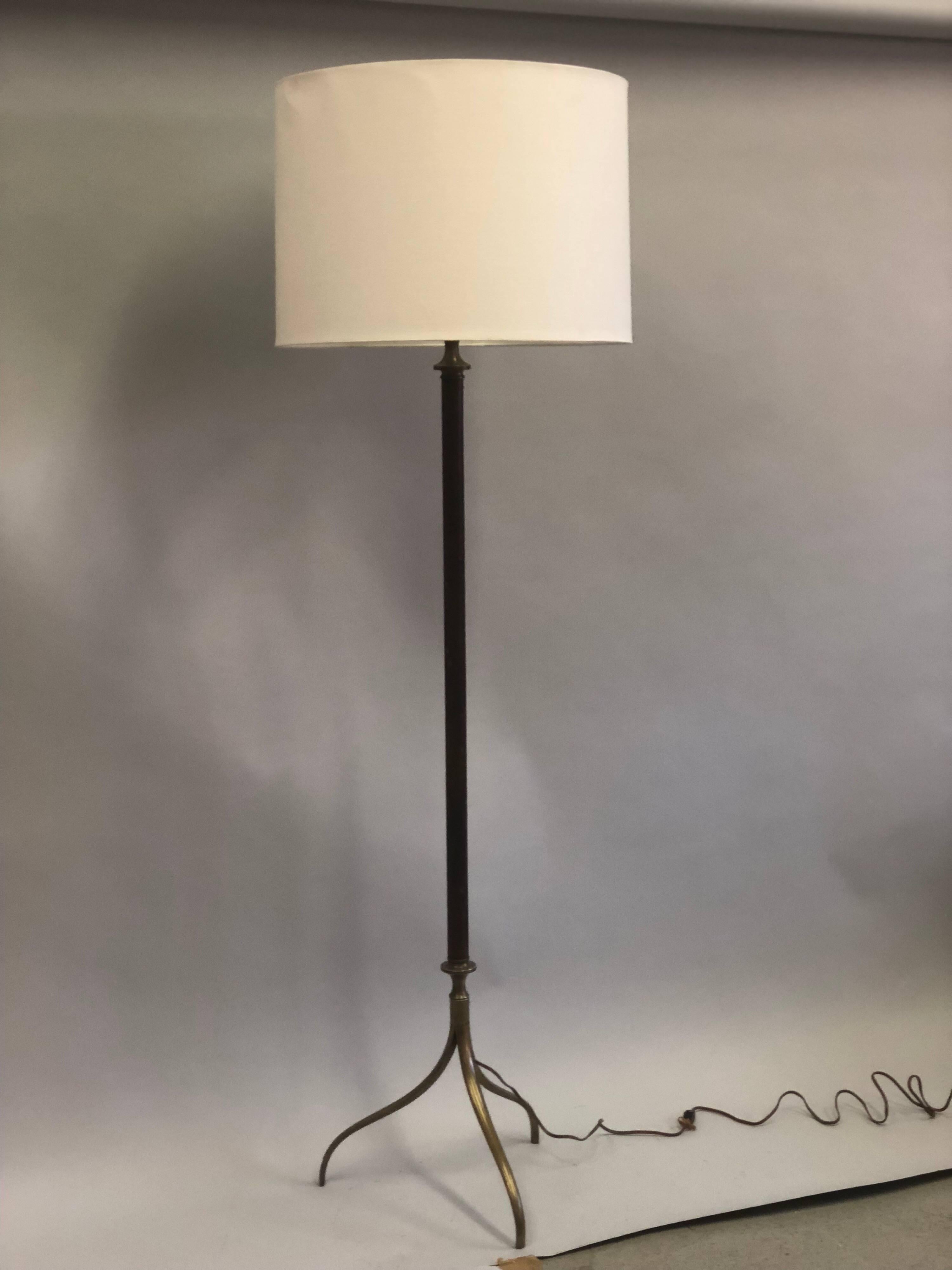Elegant French Mid-Century Modern, hand-stitched, dark brown leather floor lamp attributed to Jacques Adnet. 

The standing lamp is set on a delicate, gently curving, tapered solid brass tripod base. The dark brown leather is wrapped around the