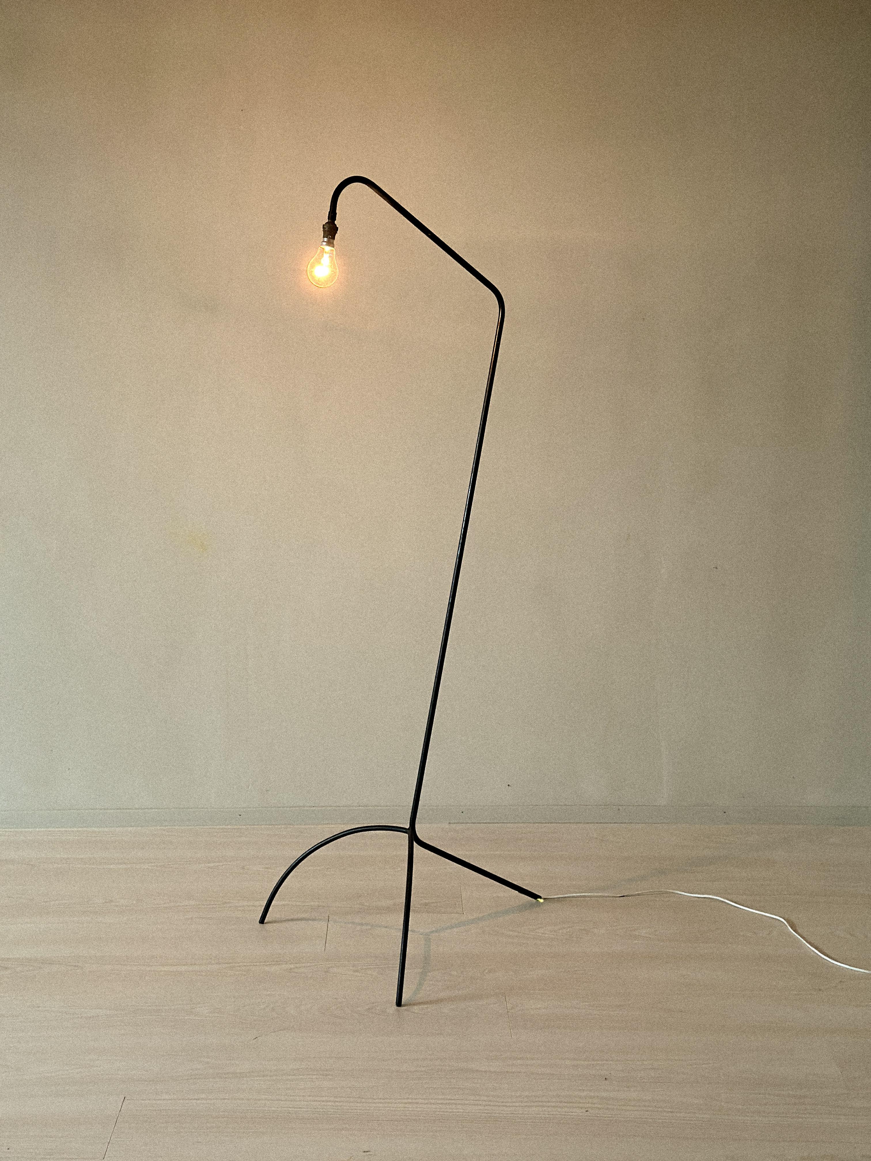 Lámpara de pie Moderna de mediados de siglo en metal curvado, Francia, hacia la década de 1950. Construcción industrial minimalista con base arqueada y bombilla vista. Laca negra original con desgaste y pátina visibles.

Desgaste propio de la edad y