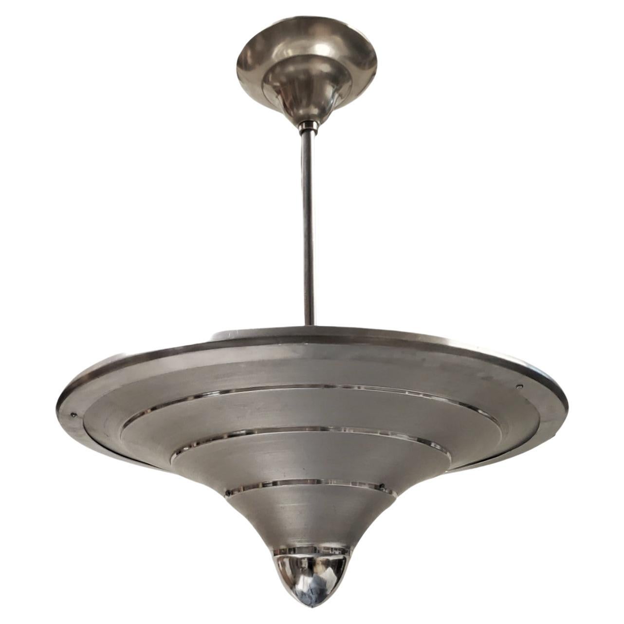 An original and unusual Mid-century, machine age pendant light  crafted from spun aluminum featuring concentric circles in alternating matte and polished finishes.  Bearing a label MAZDA to the interior.
in 1921 a firm called Compagnie des Lampes