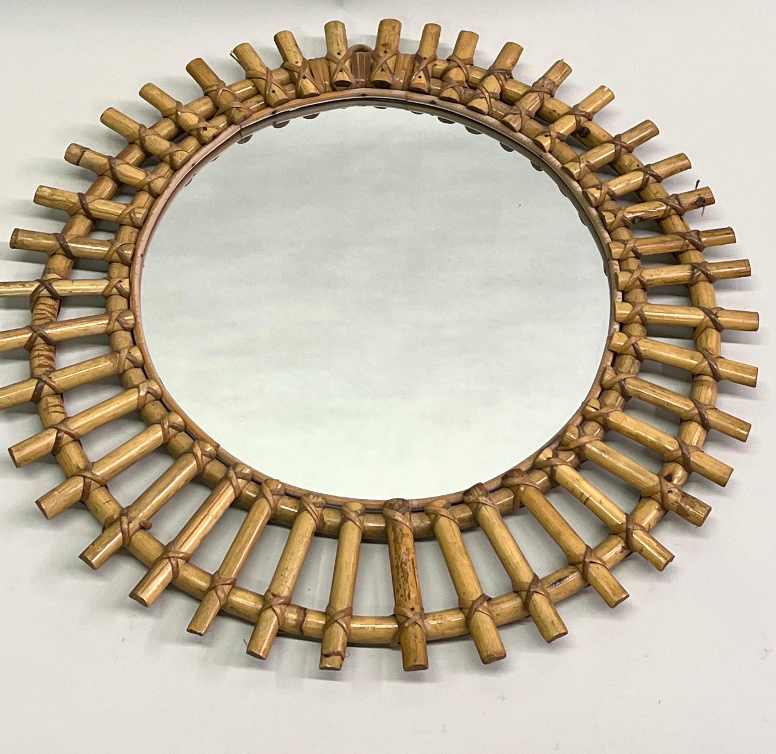 Ein eleganter französischer Midcentury Modern-Spiegel aus Bambus und Rattan. Der Wandspiegel hat eine seltene Halbmondform und weist Rattan-Sonnenstrahlen auf, die strahlenförmig von der zentralen Spiegelplatte ausgehen. Das Stück bringt die moderne