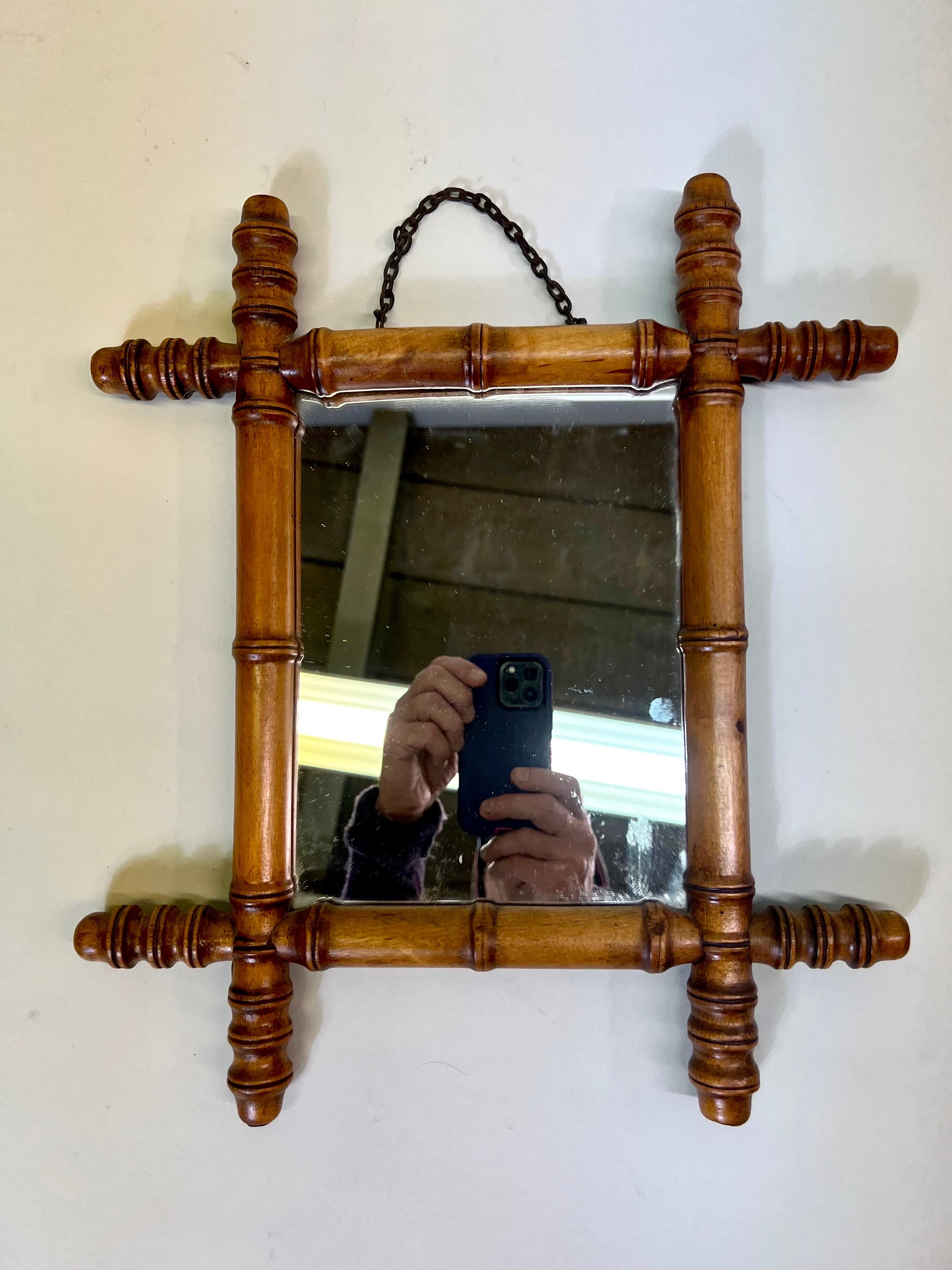 French Midcentury Modern Neoclassical mirror composed of faux bamboo and rattan in the style of Jean-Michel Frank. The piece is beautifully composed of carved and notched rattan / bamboo with ring decorations highlighting the work. The piece