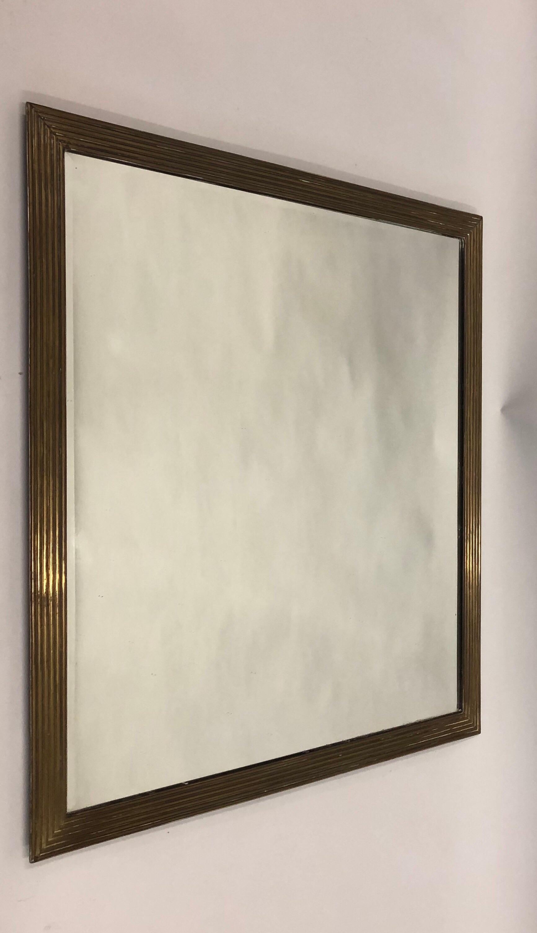 Elegant French Mid-Century Modern neoclassical solid gilt bronze mirror by Maison Ramsay, 1940.

The mirror is sober and understated and features an exquisite channeled, stepped pattern in the bronze mirror frame. The mirror plate is beveled along