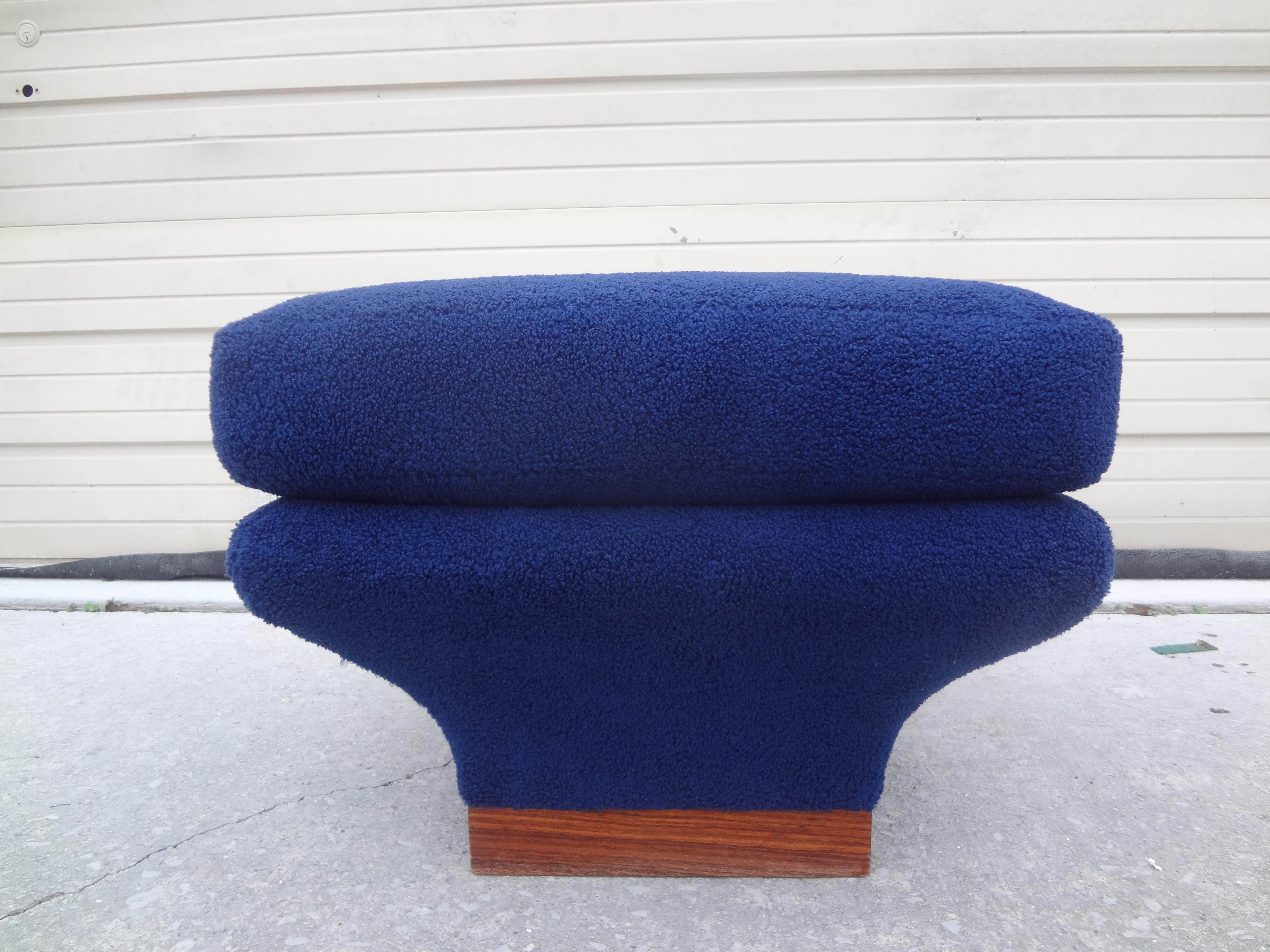 French Mid-Century Modern Ottoman Or Bench Attributed To Pierre Paulin.
Unusual French modern ottoman, pouf, stool or bench with a walnut base upholstered in plush blue boucle fabric. This handsome pouf has a semi-attached top cushion and is both