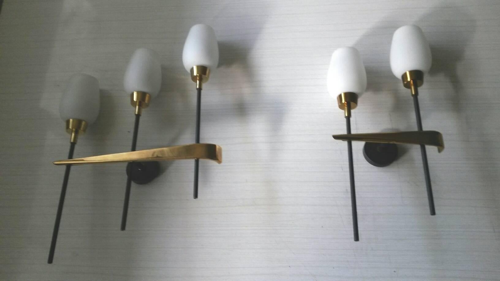 Extremely elegant pair of French midcentury sconces by Lunel. In black matte lacquered metal and satin white opaline, France, 1950s.
Important: The pair of sconces is composed by:
Important : one three-arm sconce and the other is a  two-arm
