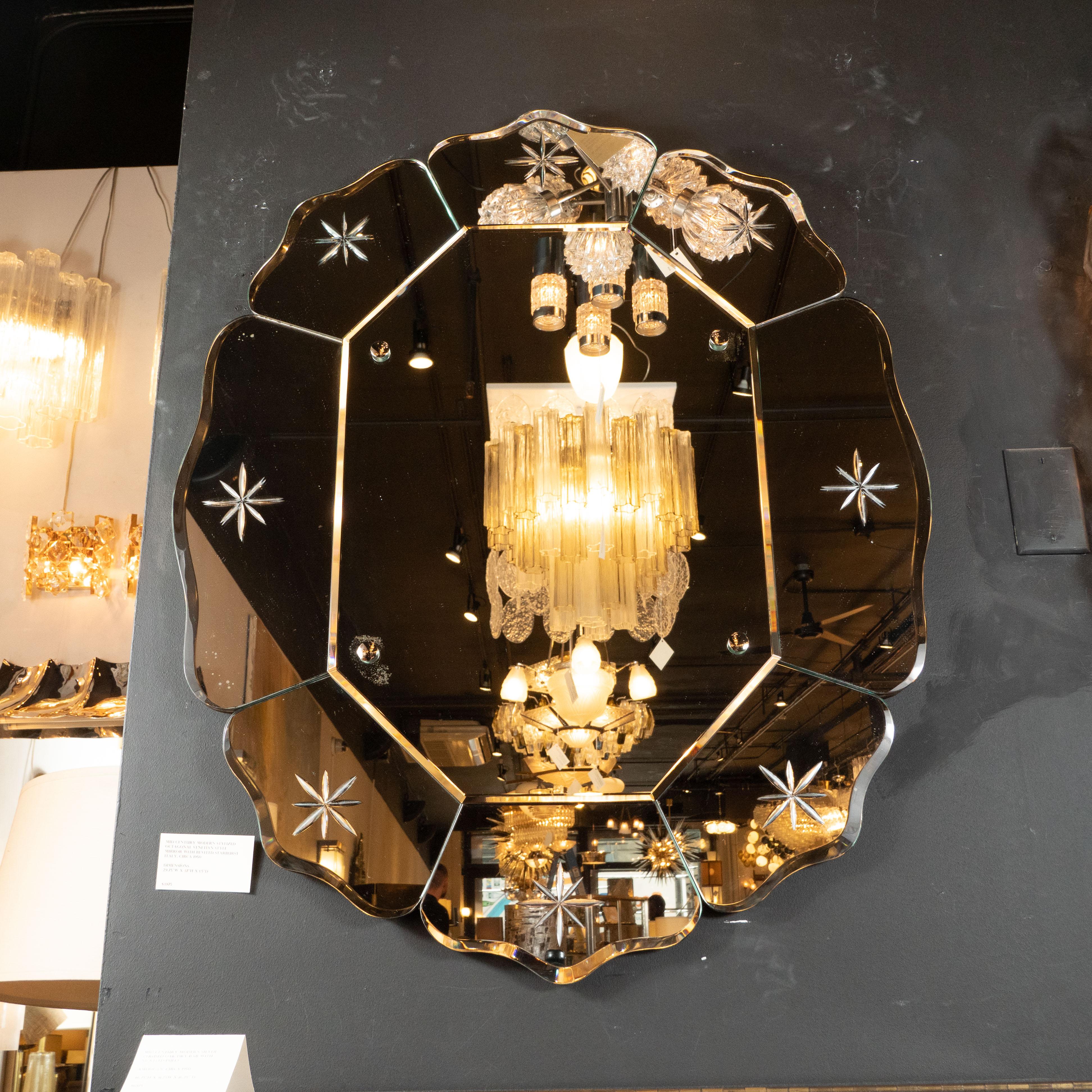 This elegant Mid-Century Modern wall mirror was realized in France, circa 1950. It features eight mirrored panels with beveled edges with etched eight point stylized star motifs in the center of each that surround a central octagonal mirror, secured