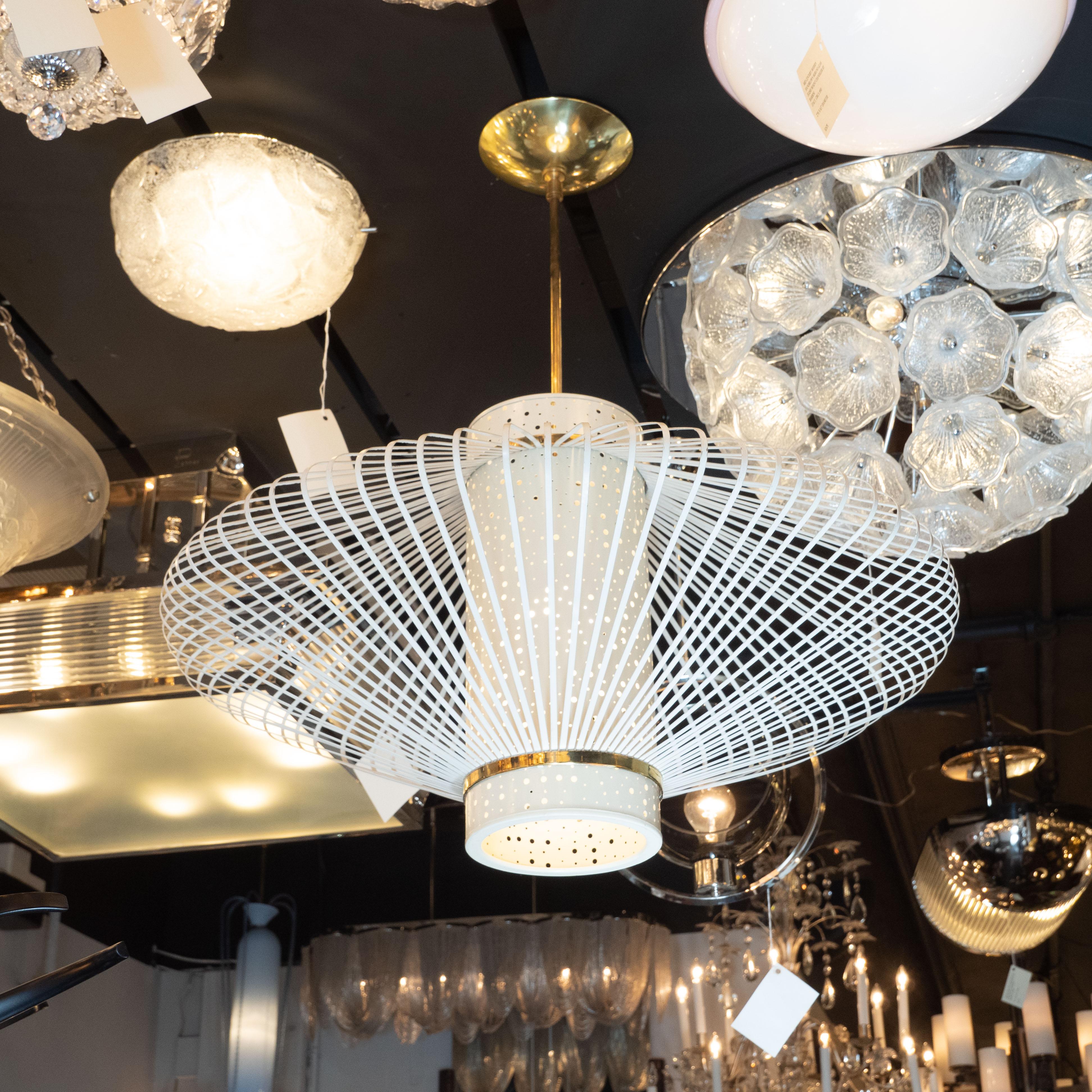This sophisticated and sculptural chandelier was realized in France, circa 1950. It features a cylindrical body painted in cream hued enamel perforated with an abundance of holes of differing diameters that allows the light to softly diffuse into