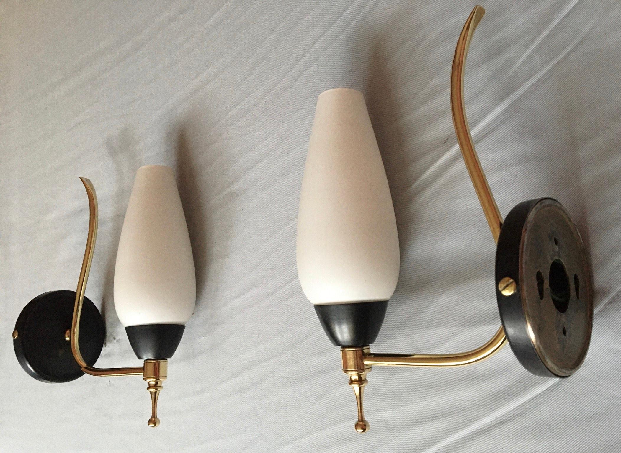Beautiful pair of midcentury French 1950s sconces in brass, black metal painted, and white satin opaline shade.

The pair is in a very good condition, electricity has been renewed and fits the US Standard (screw bulb holder, 60 watts per shade