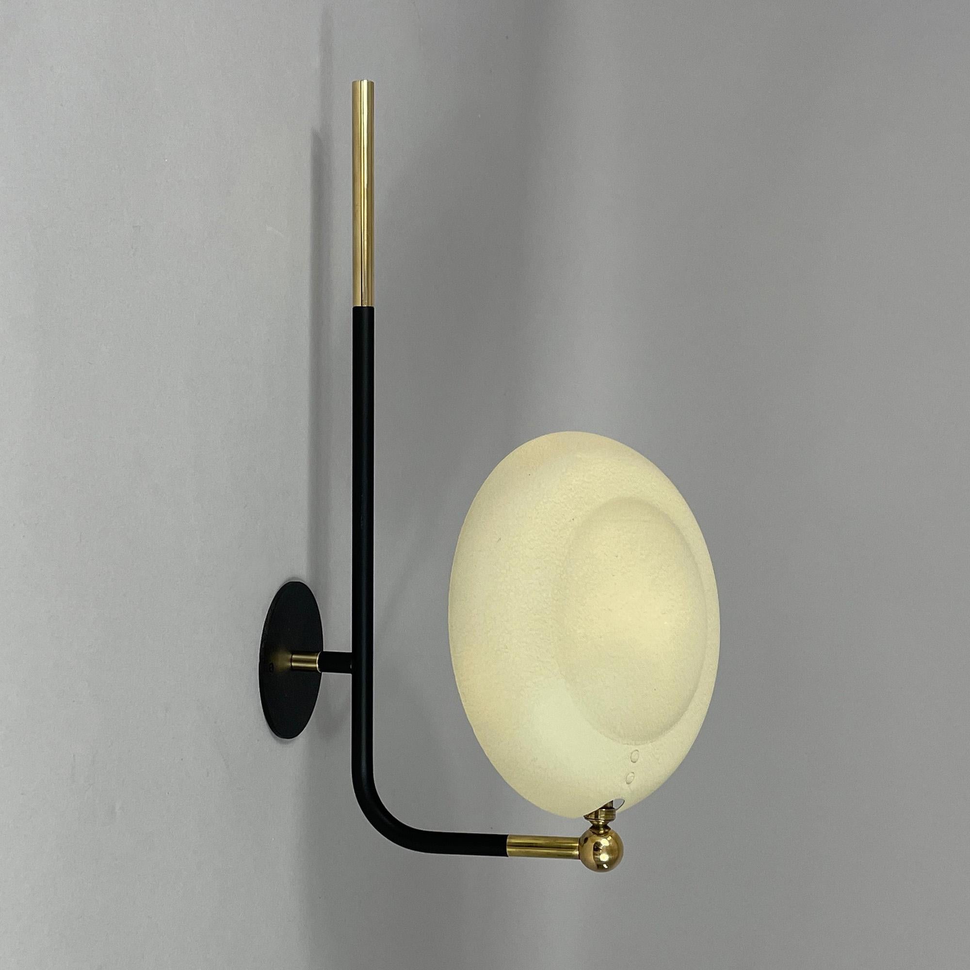 This wall light was designed and manufactured in France in the 1950s. It has a minimalist, modernist design, typical of mid-century French lighting styles.

The light features an adjustable dark ivory / cream colored lamp shade with wrinkle lacquer