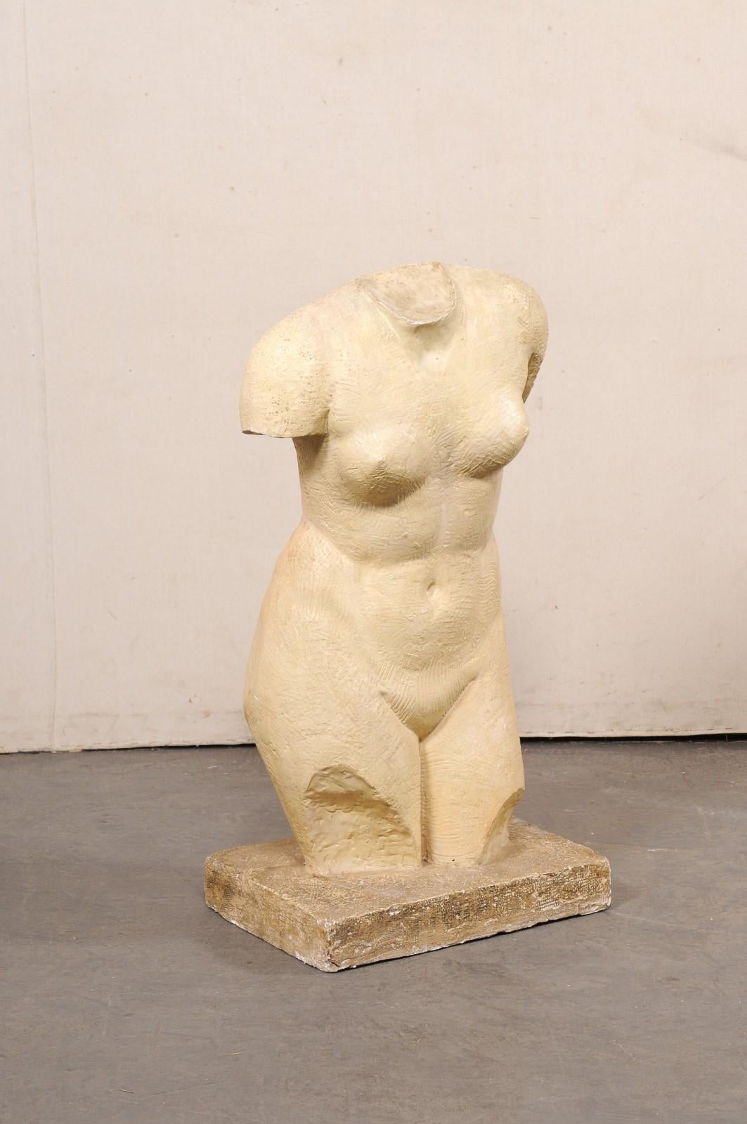 A French artistic nude female torso statue from the mid 20th century. This plaster sculpture from France depicts a nicely curved female torso, the mid-region from neck to knee, raised upon a rectangular-shaped platform base. The subject is slightly