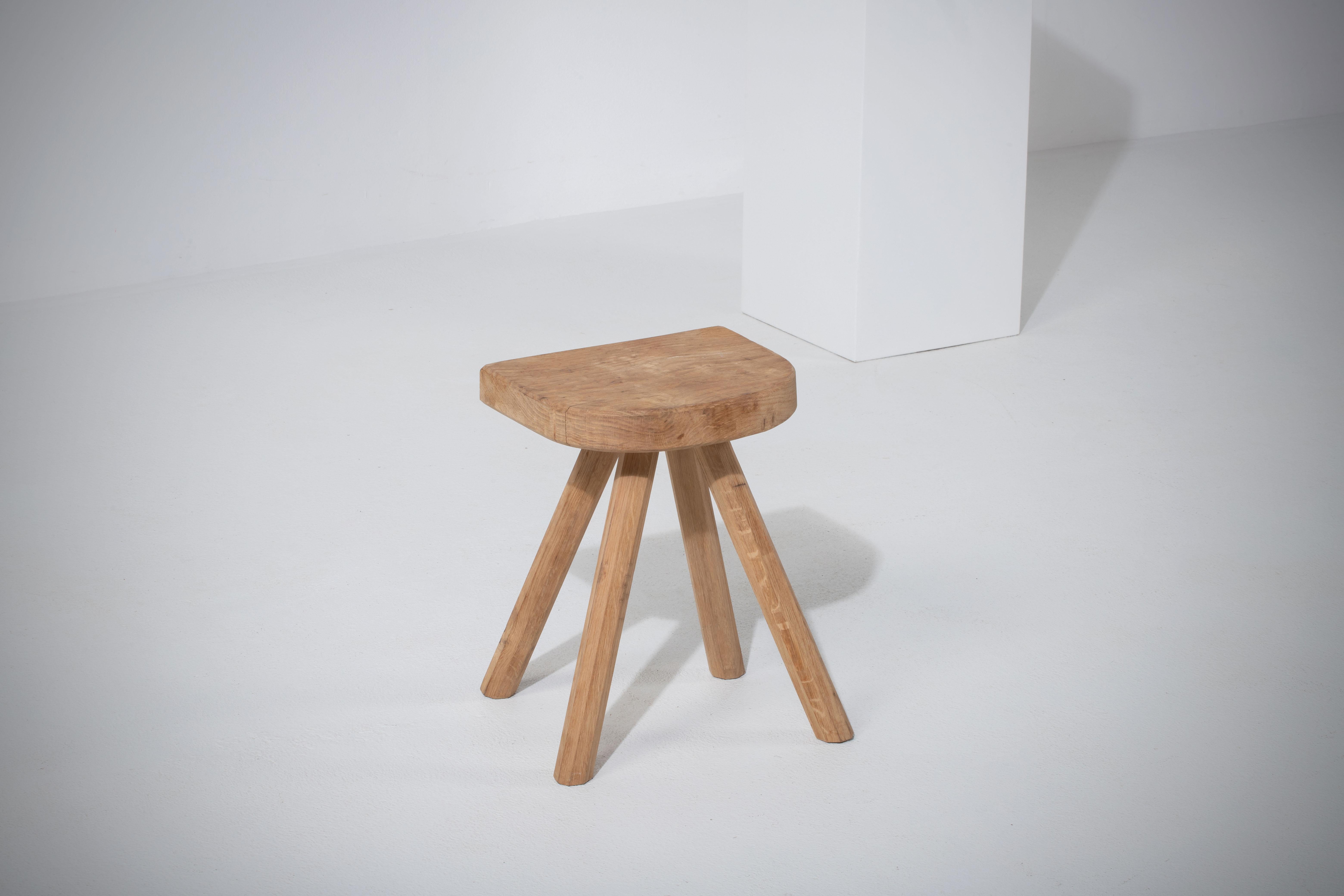 Introducing a captivating midcentury stool from France, exhibiting tripod flared feet and a gracefully simplistic design. Crafted from solid and raw natural oak, this stool embodies the spirit of unrefined elegance. The sturdy construction and