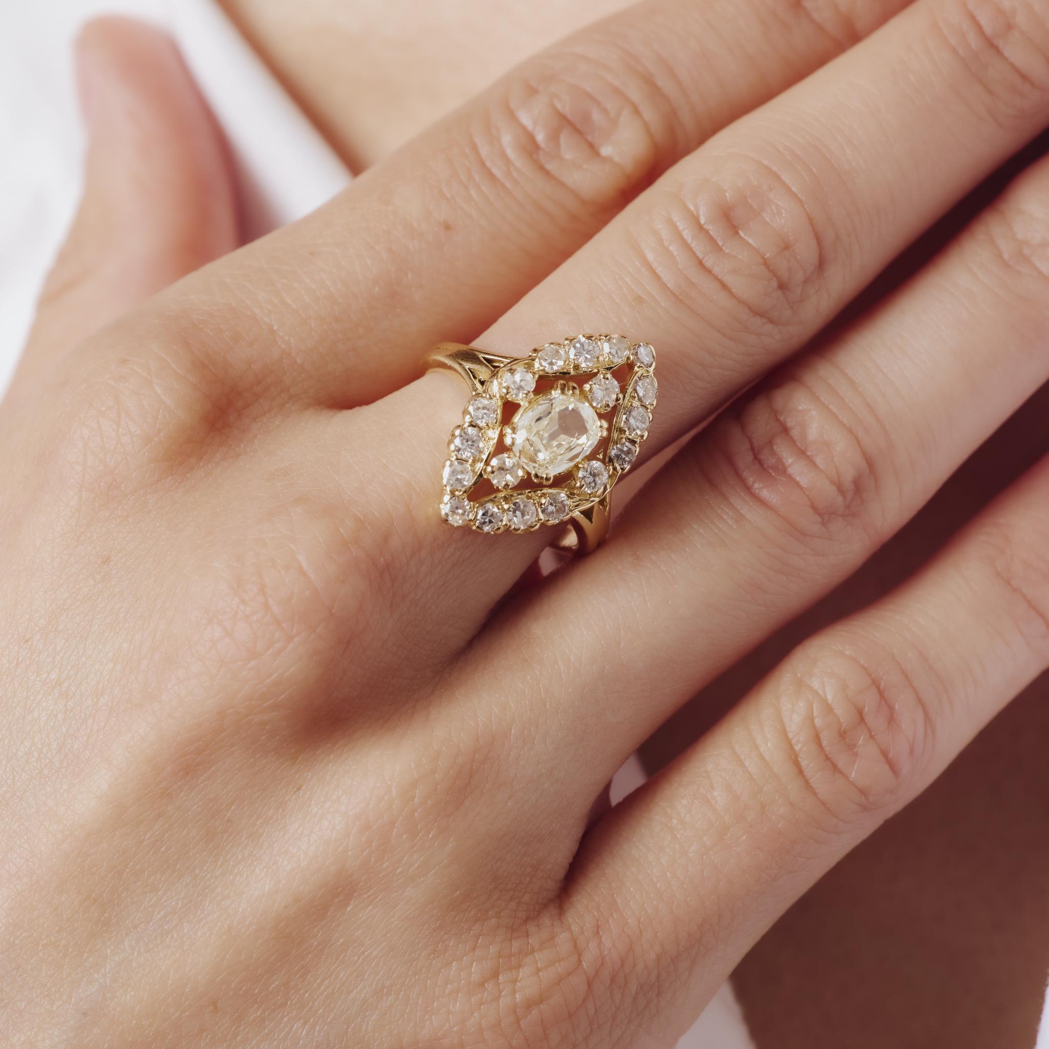 Cette bague du milieu des années 1960 brille avec un diamant taille ancienne de 0,81 carat encadré par 18 diamants transitionnels et taille unique étincelants, tous magnifiquement sertis dans un riche or jaune 18 carats marqué par la France.