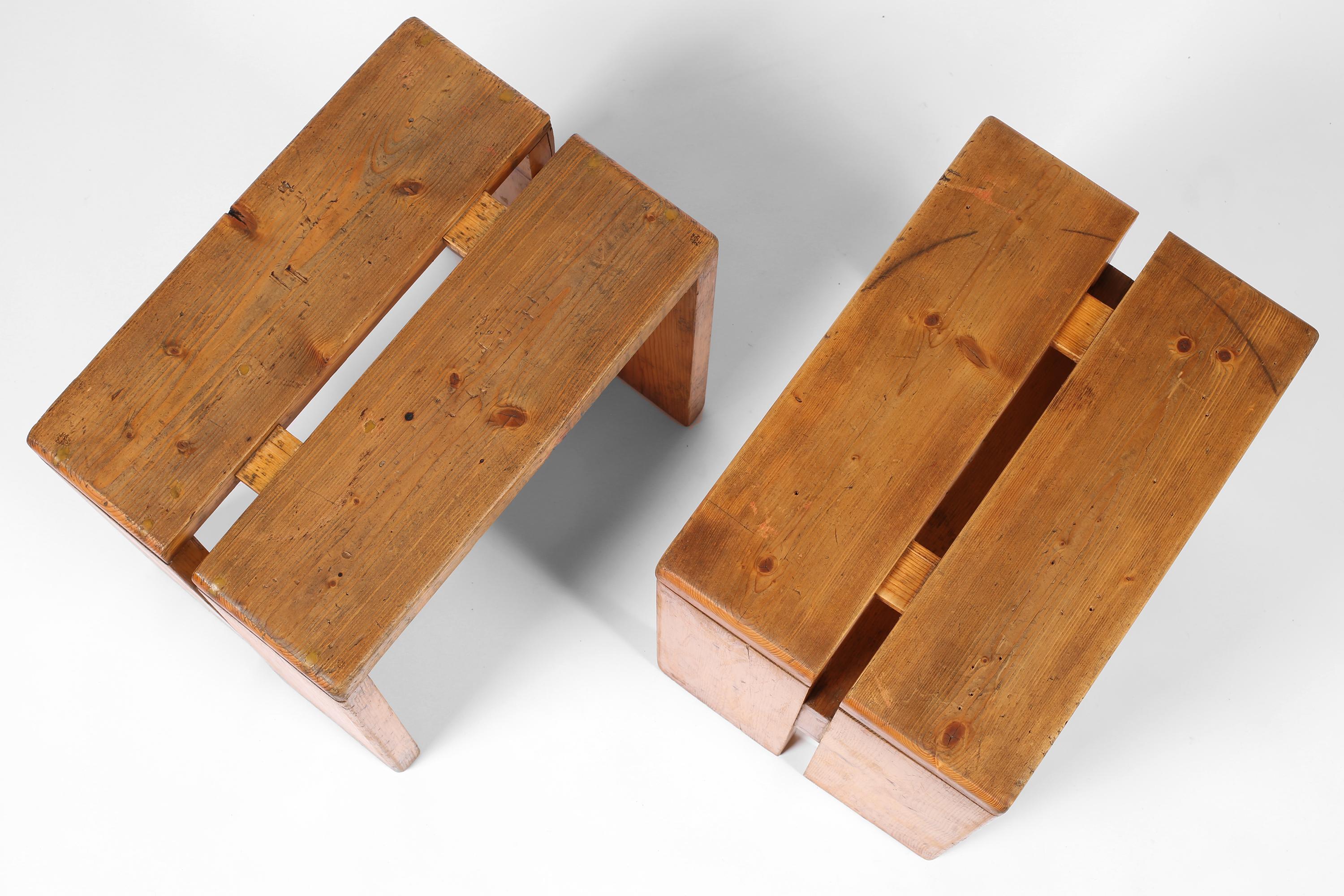 Una coppia di sgabelli classici originali in pino disegnati da Charlotte Perriand (1903-1999) per la stazione sciistica di Les Arcs. Storicamente patinati, iconici e architettonici nel loro design, sono adatti come tavolini. Francese, 1960 circa.