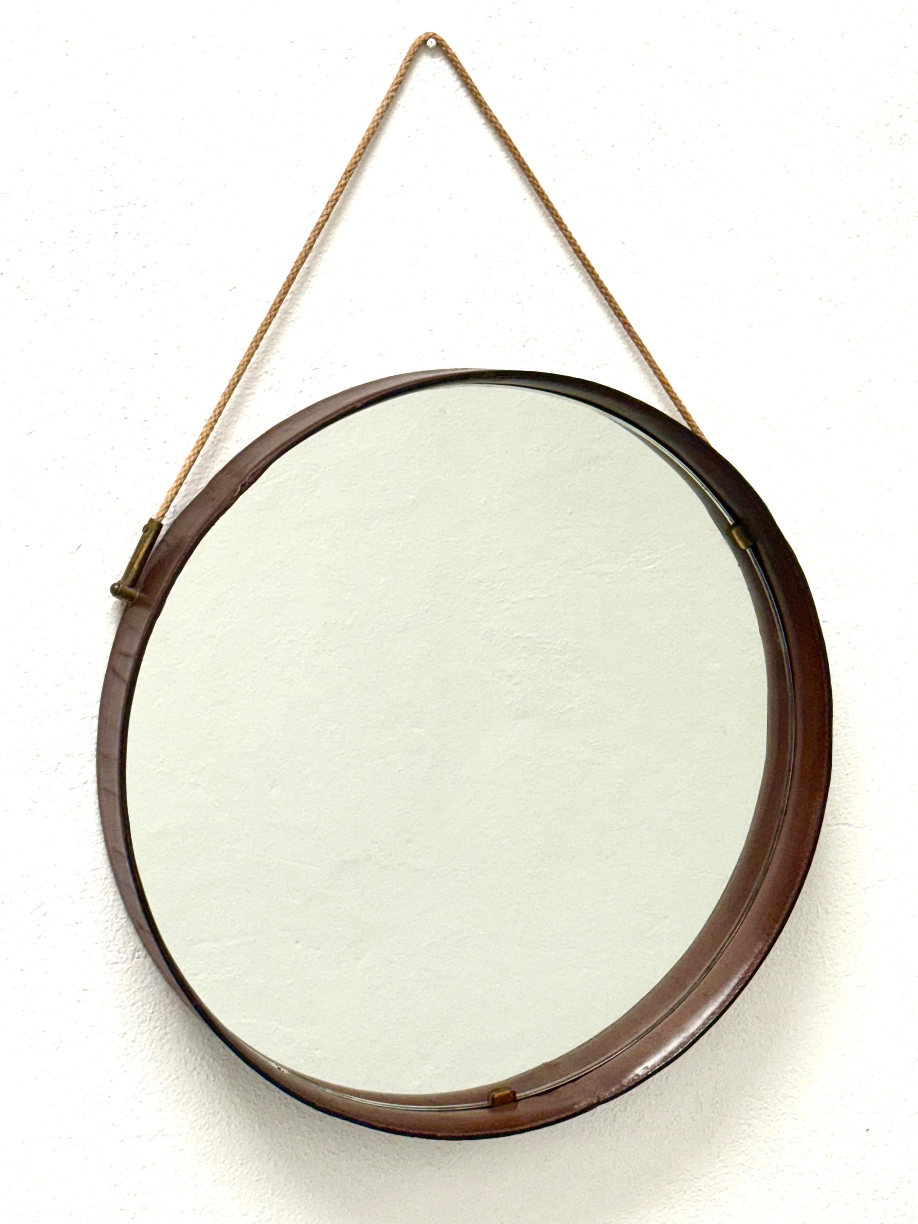 An Elegant French Mid-Century Modern Round Stitched Dark Brown Leather Mirror Attributed to Jacques Adnet circa 1955. This authentic, period mirror is clad in leather that is over 2.5